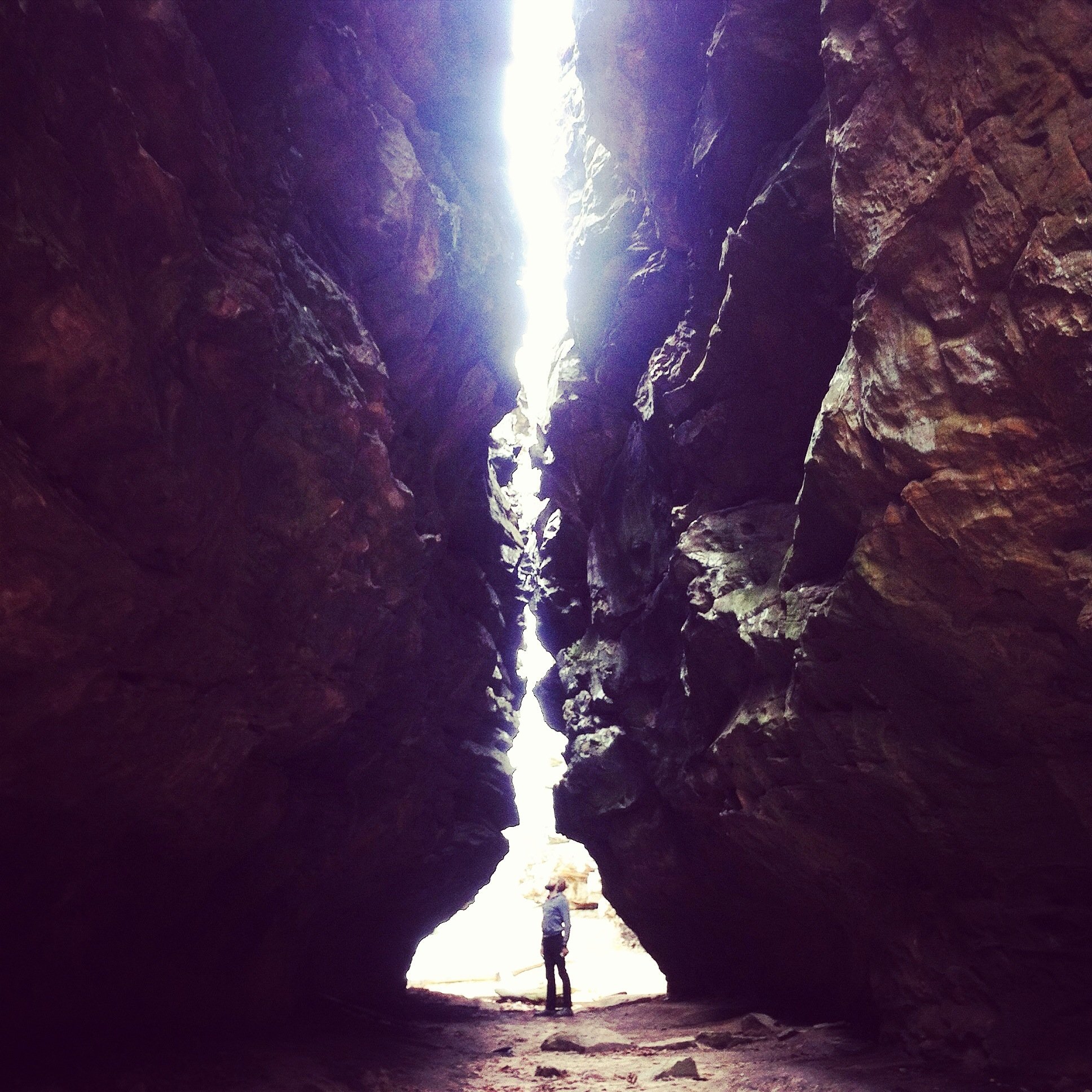 Person standing in a gap between two large rocks.