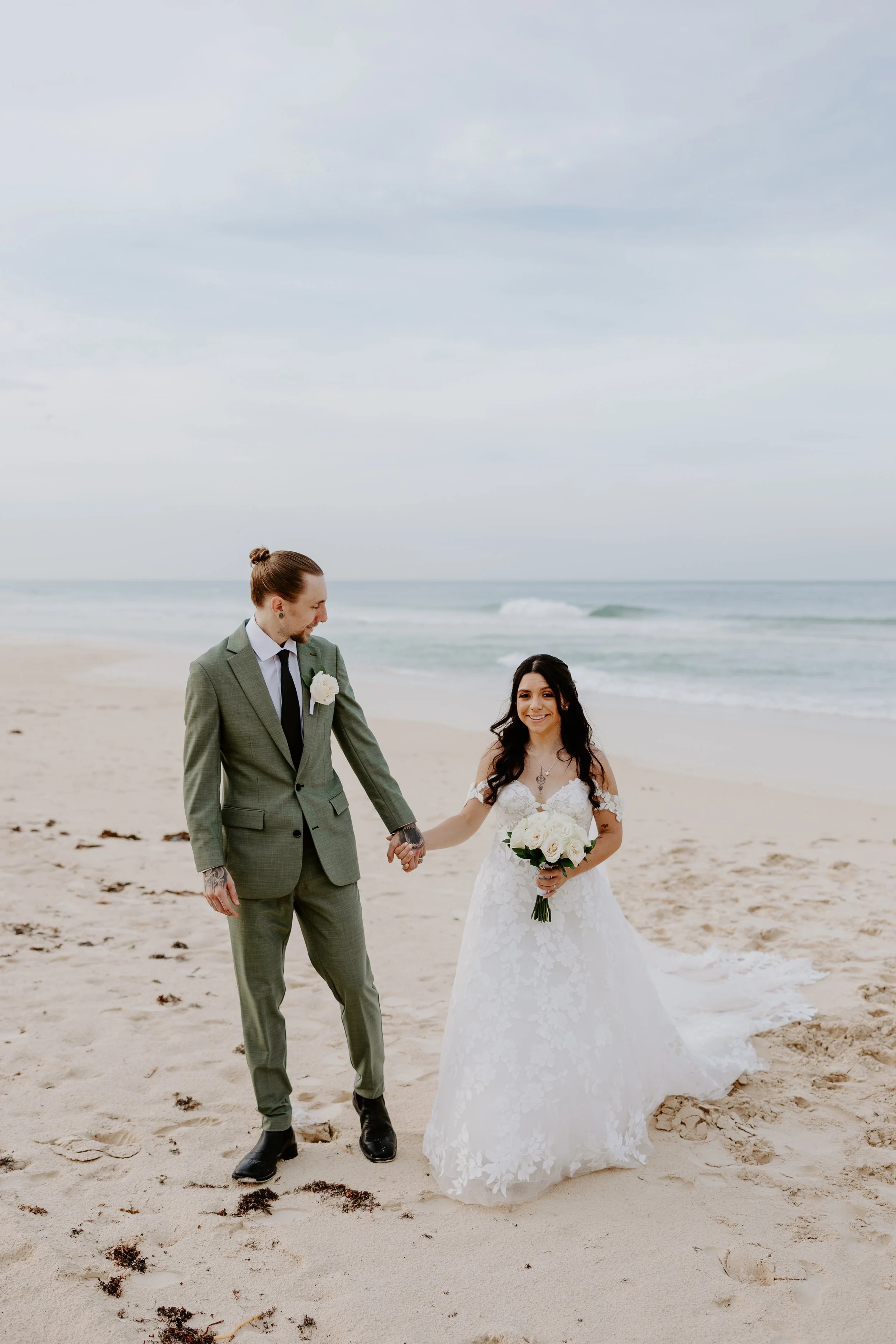 A newly wed couple walks on the beach