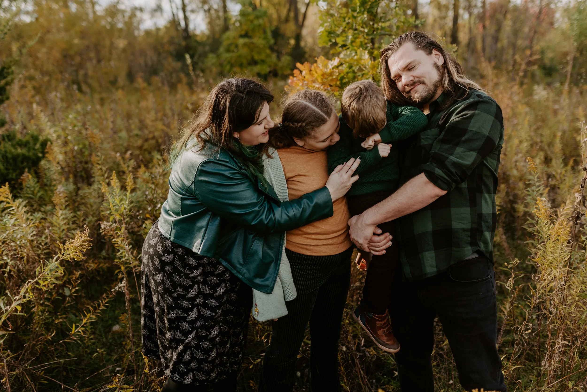 A family of four skips through tall grass at golden hour