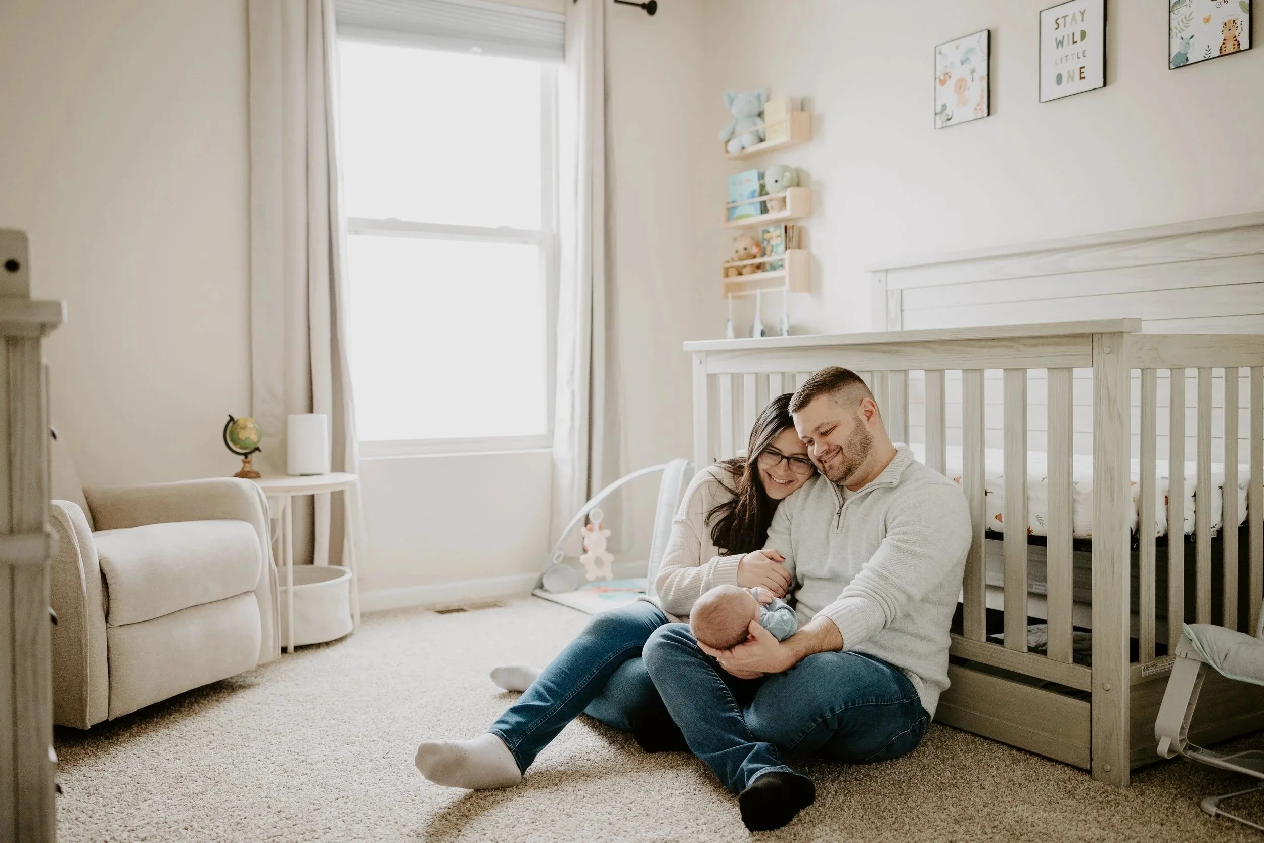 a couple is sitting on their nursery floor holding their newborn