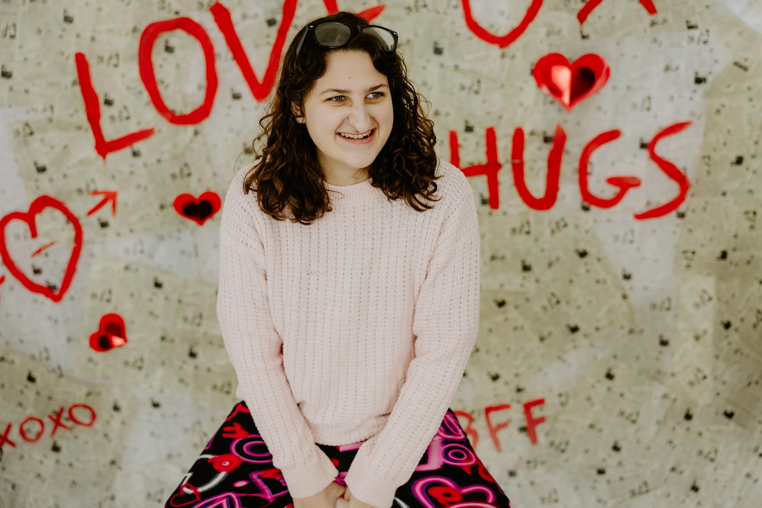 A girl smiles and looks off to the side in front of a newspaper backdrop