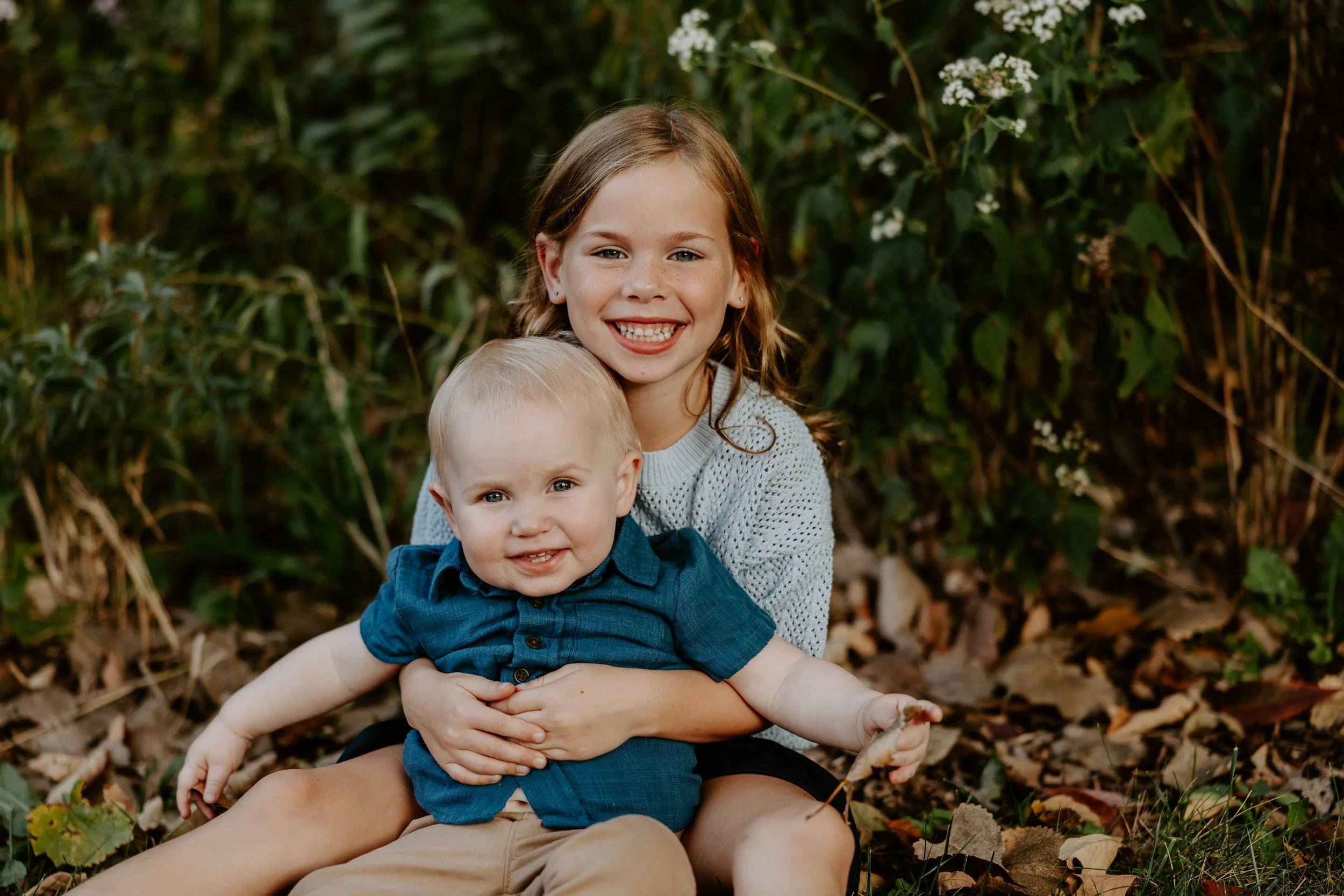 A smiling sister holds her little brother