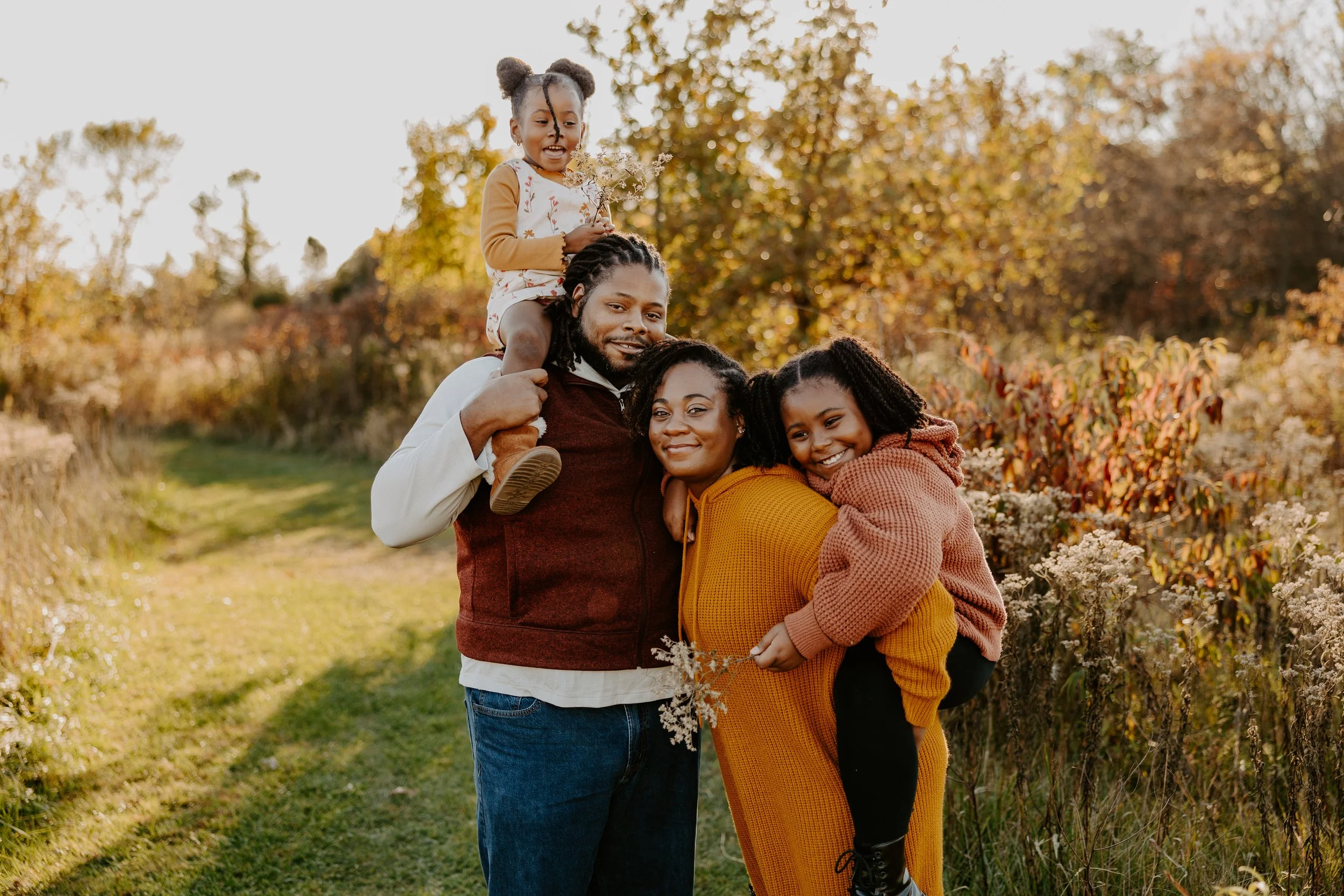 two parents give their daughters piggy back rides
