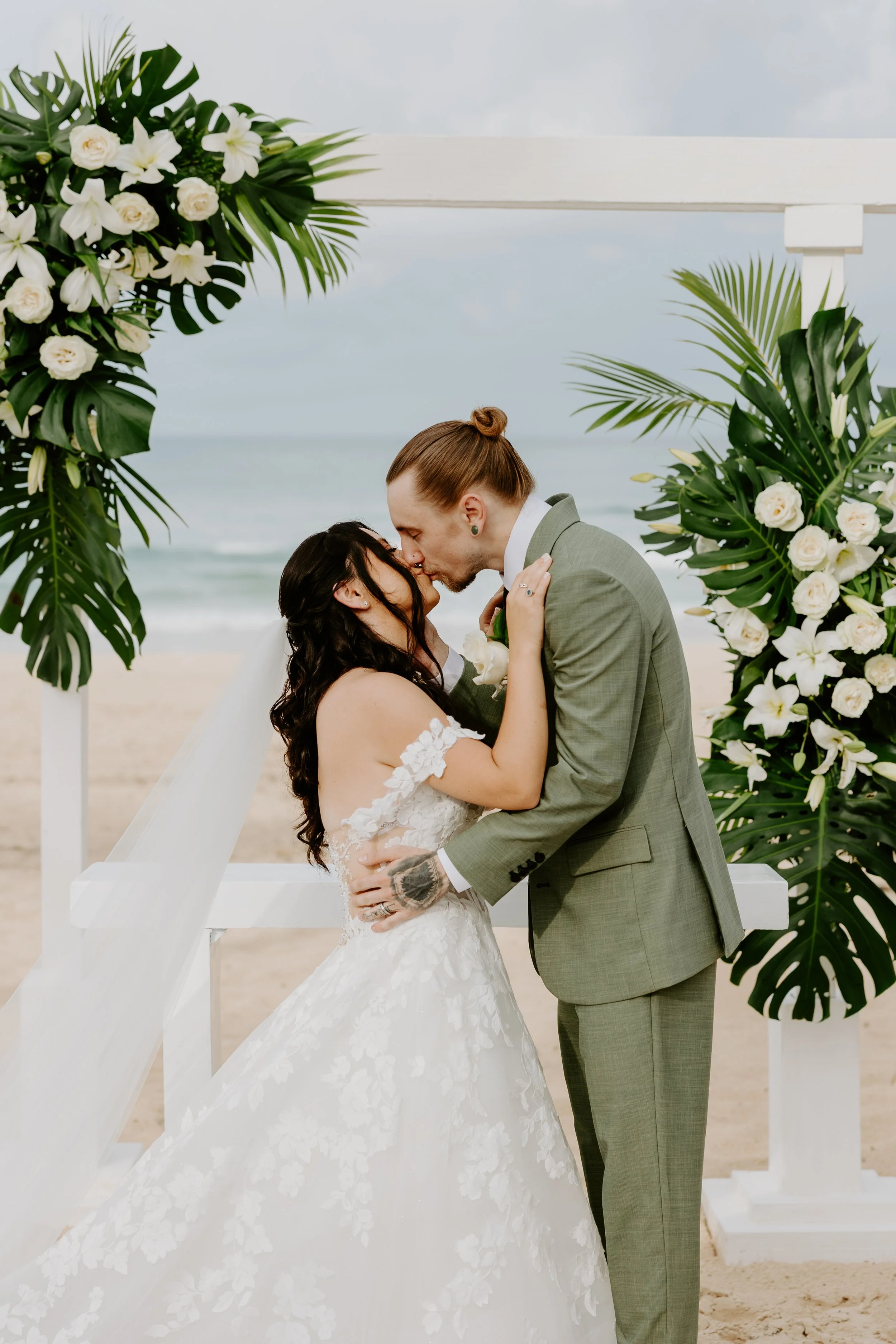 A bride and grooms first kiss on the beach