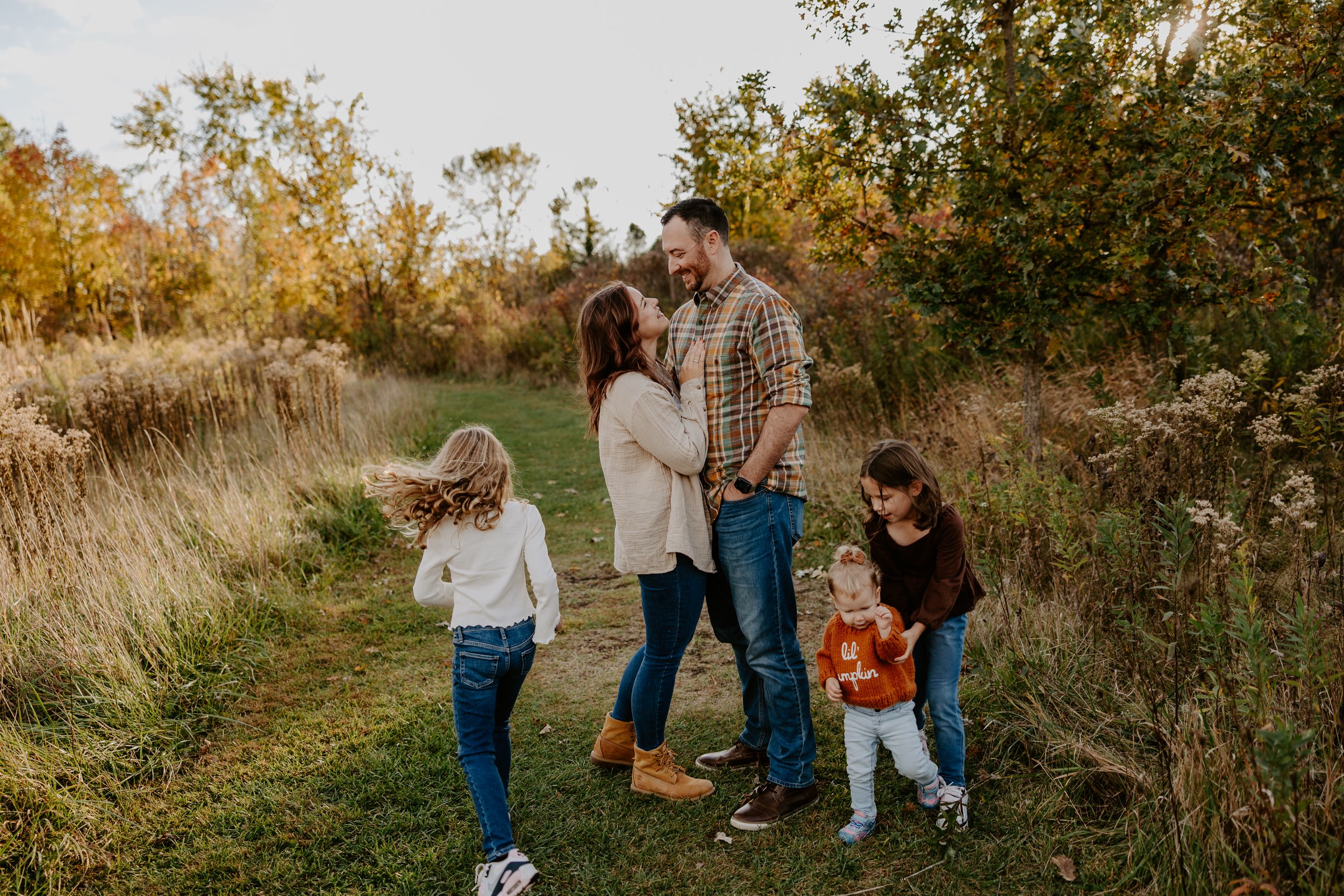 Mom and Dad look at each other while their three kids run around them