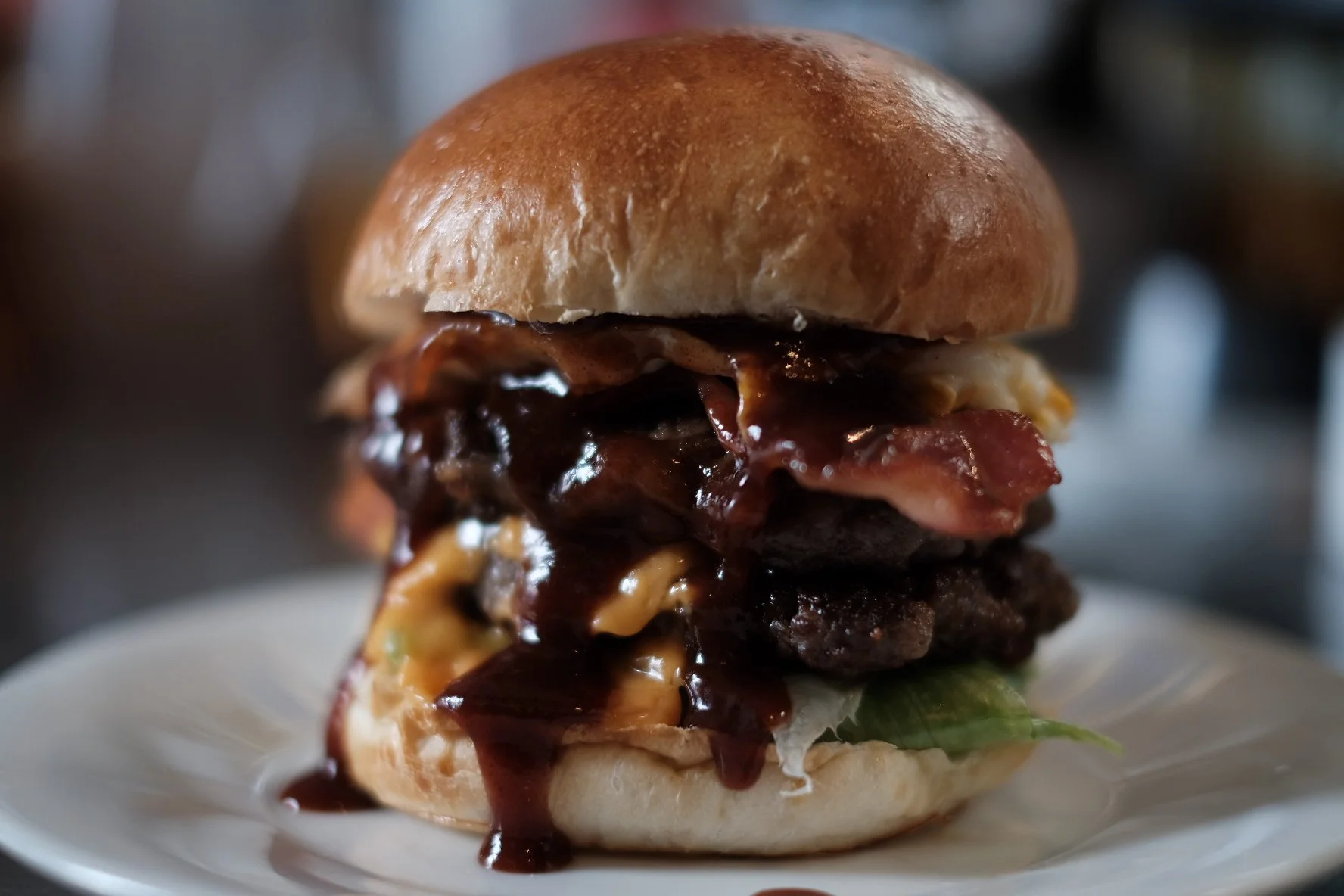 ハンバーガー。バンズの上下に肉、レタス、トッピングとソースが見える。