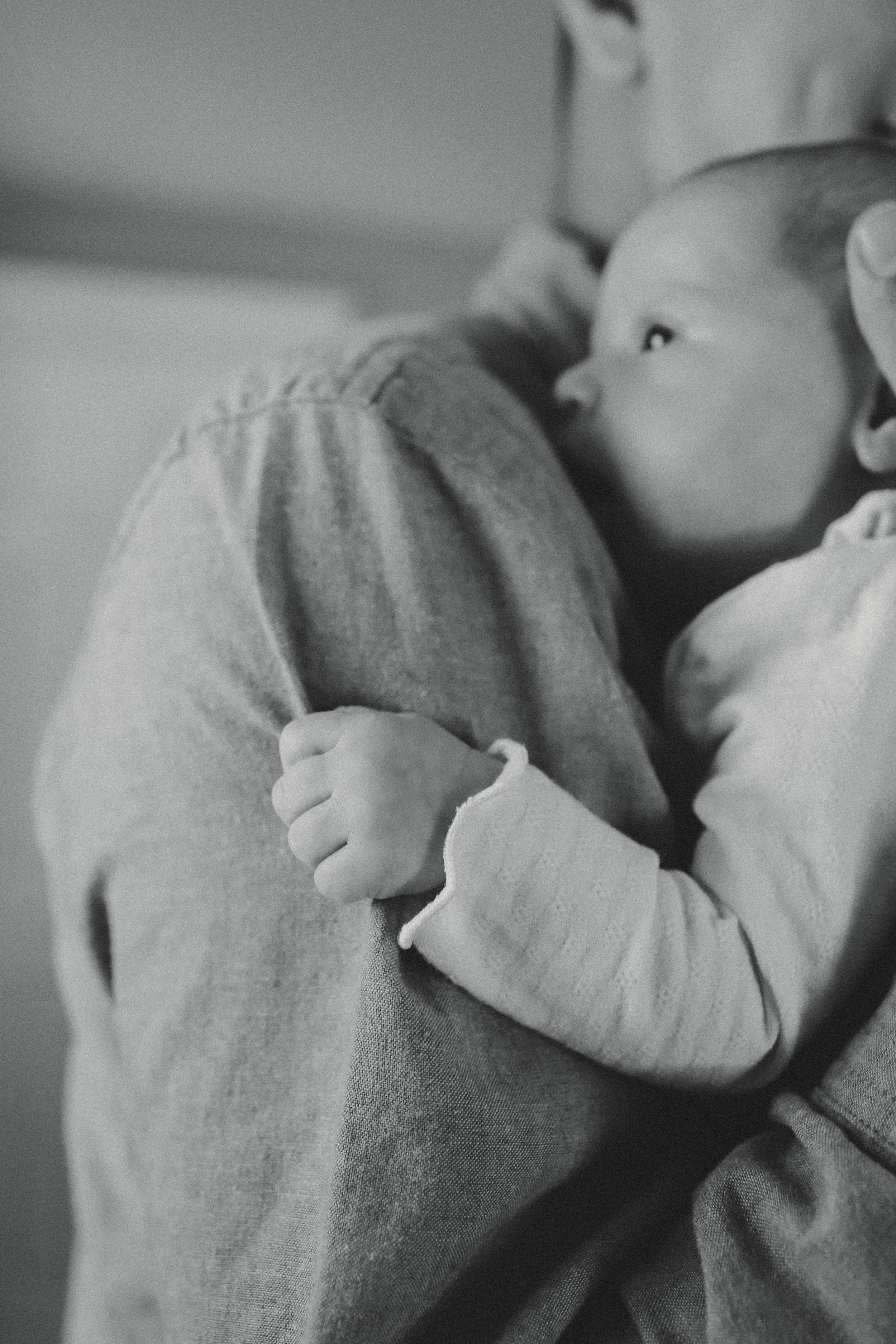 A person holding a baby close to their chest. The baby looks up at the person with curiosity.
