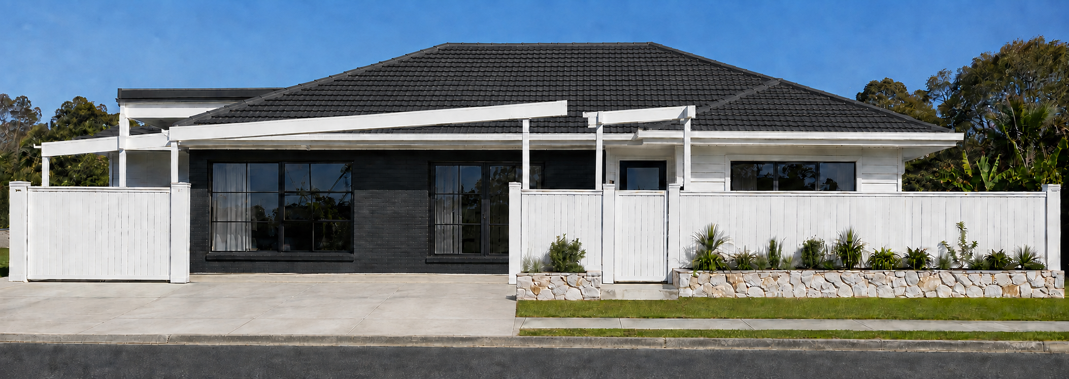 Front view of a modern house with a black tiled roof, white fence, and a small front garden with plants, sidewalk, and street.