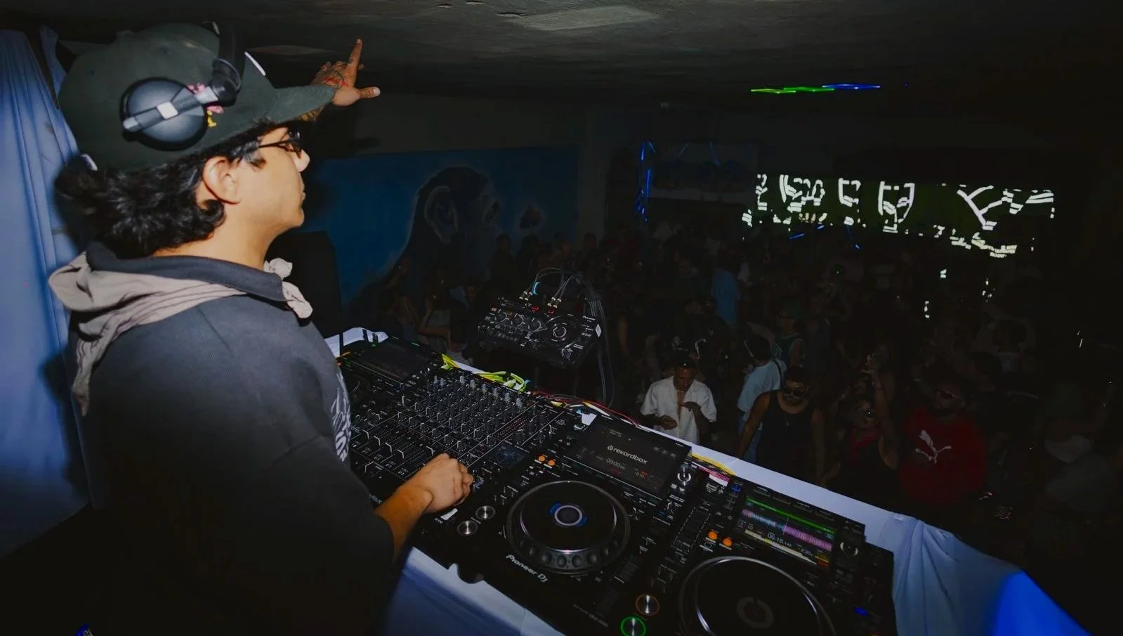 DJ performing at a nightclub with a crowd dancing in the background.