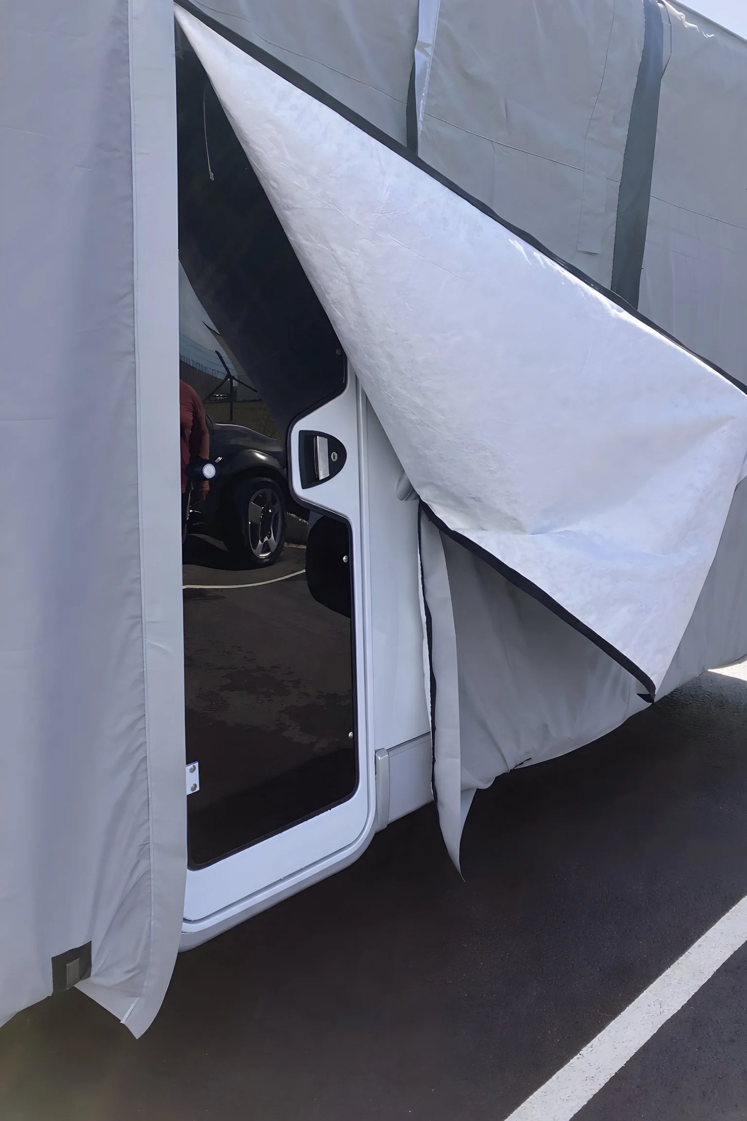 Person standing next to an RV with a pop-out section extended, revealing the interior of the vehicle.