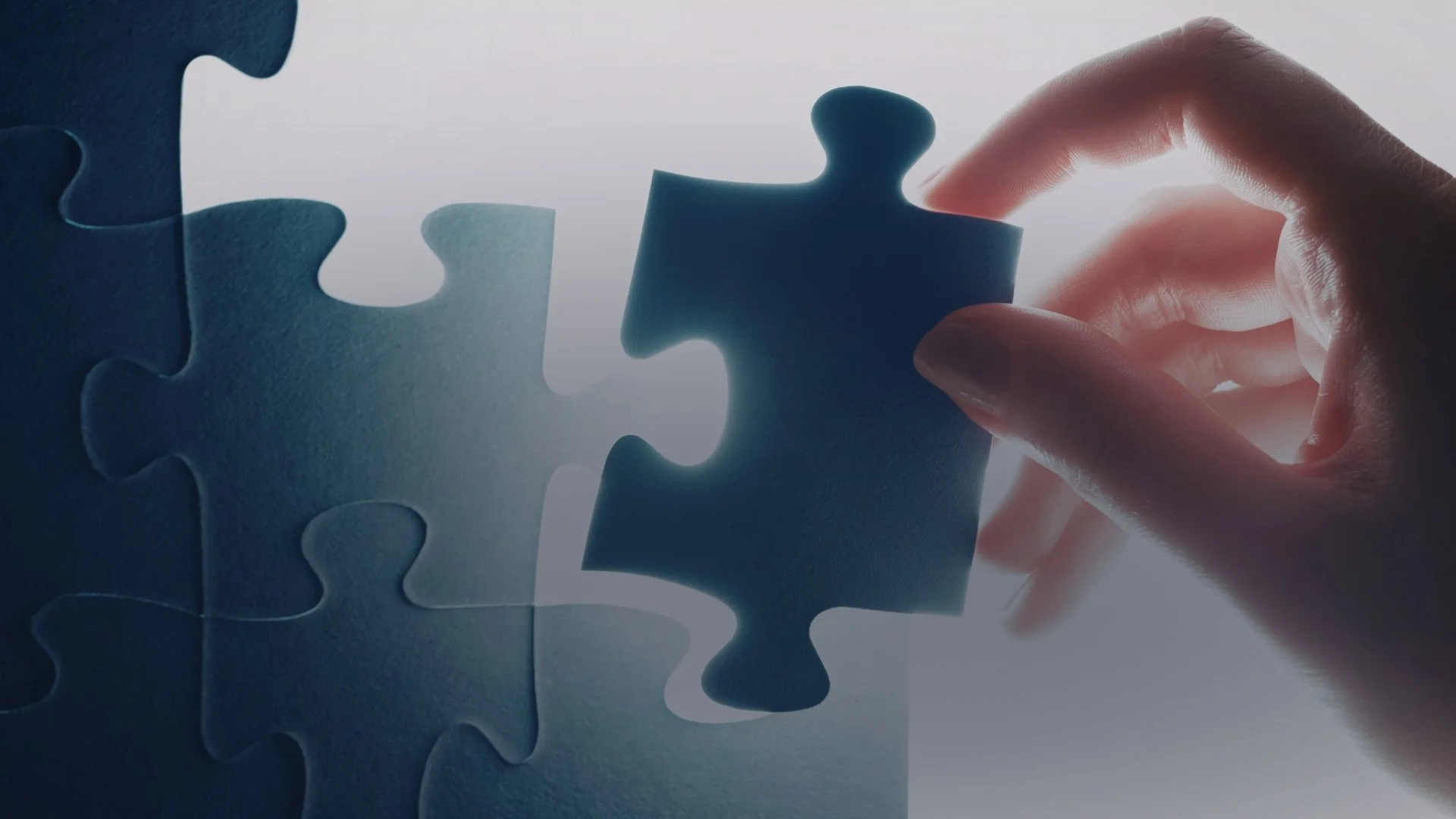 Hand placing the final puzzle piece into a partially completed blue puzzle.