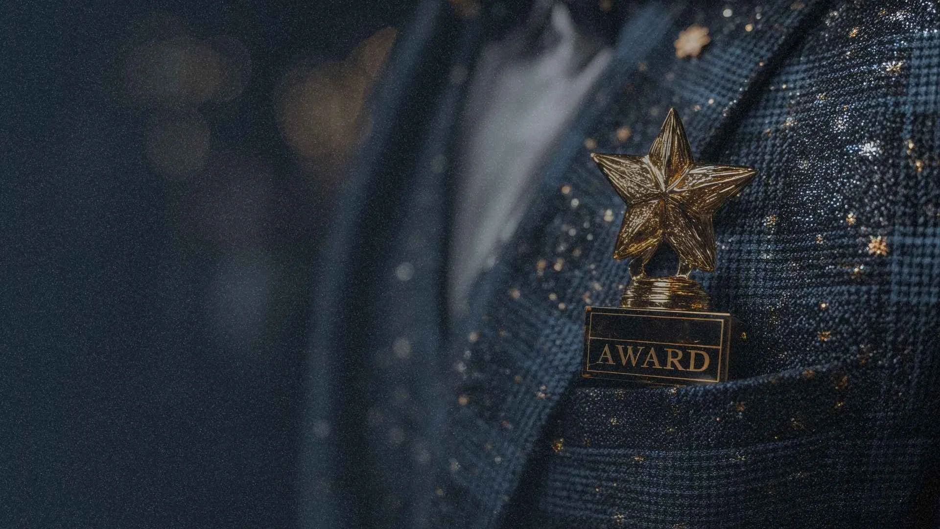 Gold star trophy on a dark surface with scattered gold particles