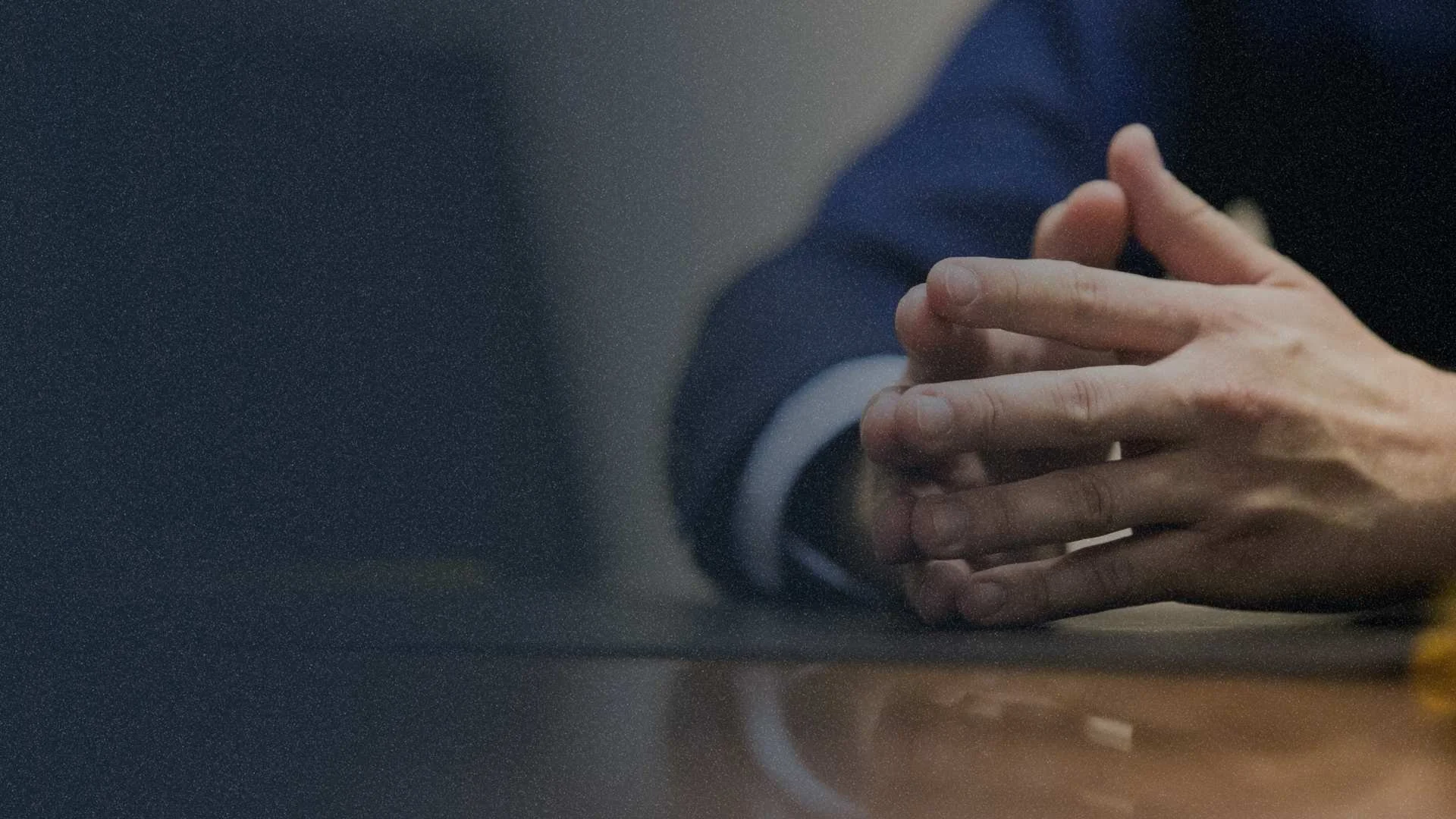 Close-up of hands in a boardroom setting, representing AI governance questions for communications firms