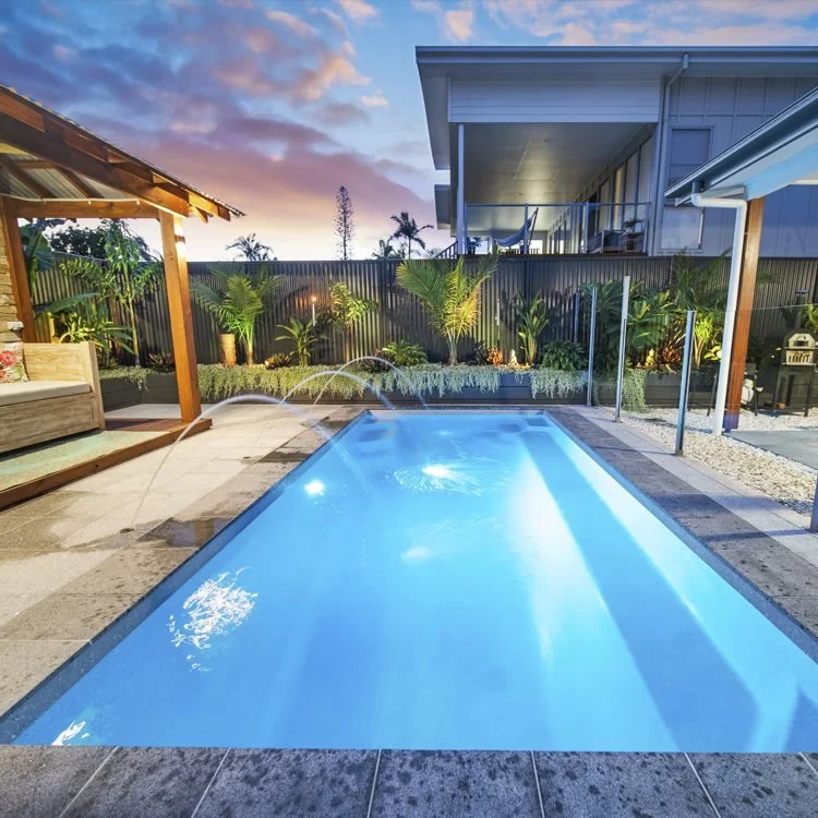 Freedom Pools Entertainer 5.5m fibreglass pool with outdoor entertaining area at dusk - available through Plungeit Pools Queensland