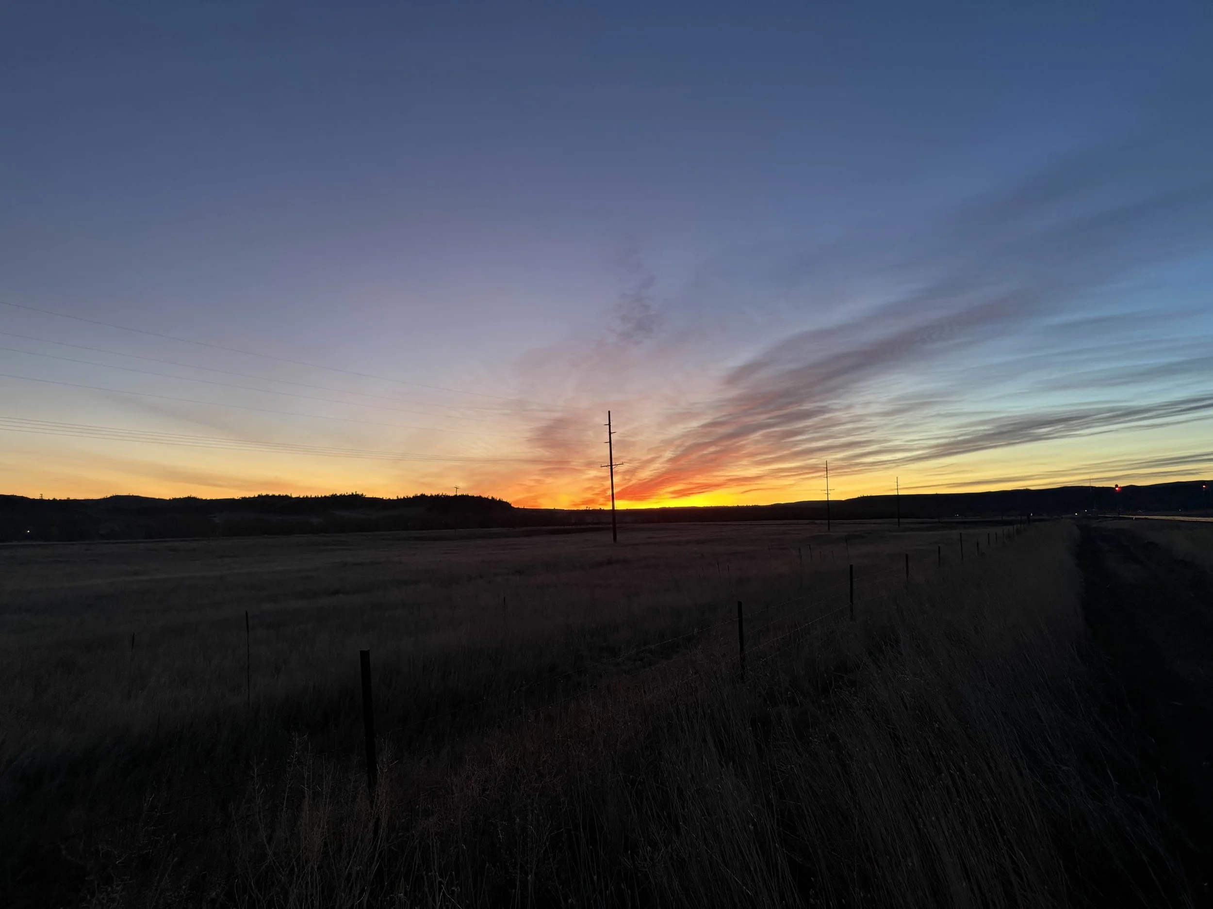 Colorful Montana sunset over open fields with fence and telephone poles – Cradle of Life LLC