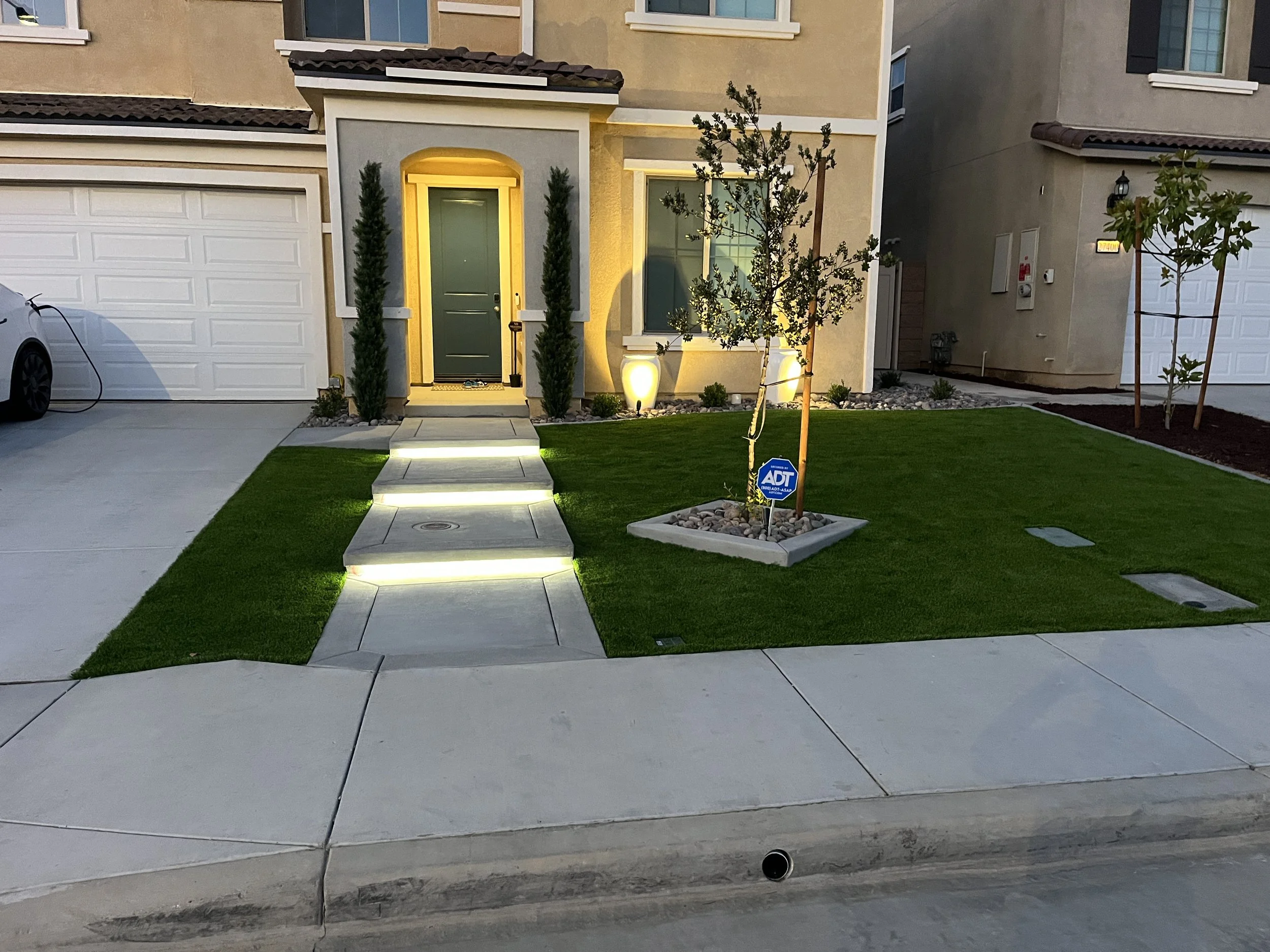 Front yard concrete and landscaping project in Murrieta featuring smooth concrete walkways, turf installation, and modern lighting details.