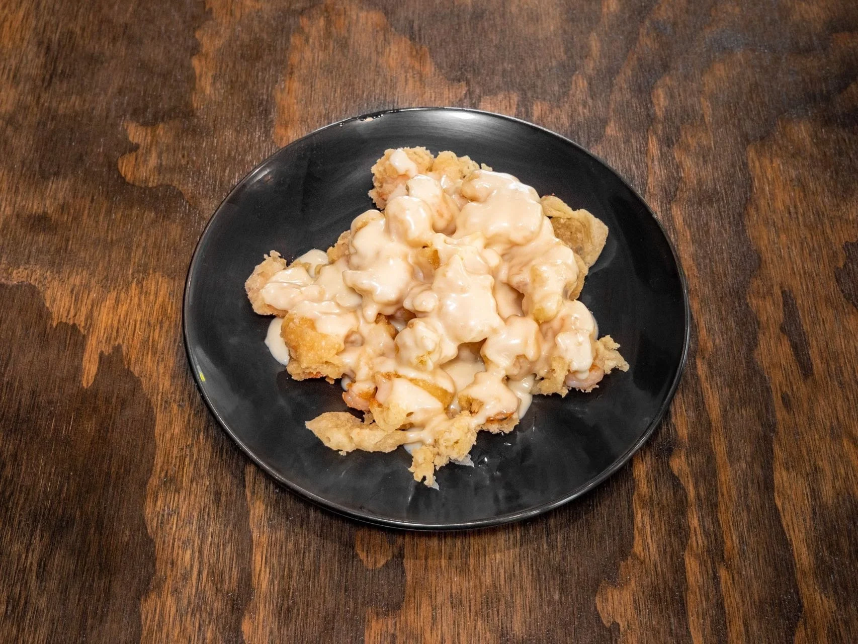 A plate of chicken and vegetable pot pie with a flaky crust and a creamy filling, served on a black plate on a wooden table.