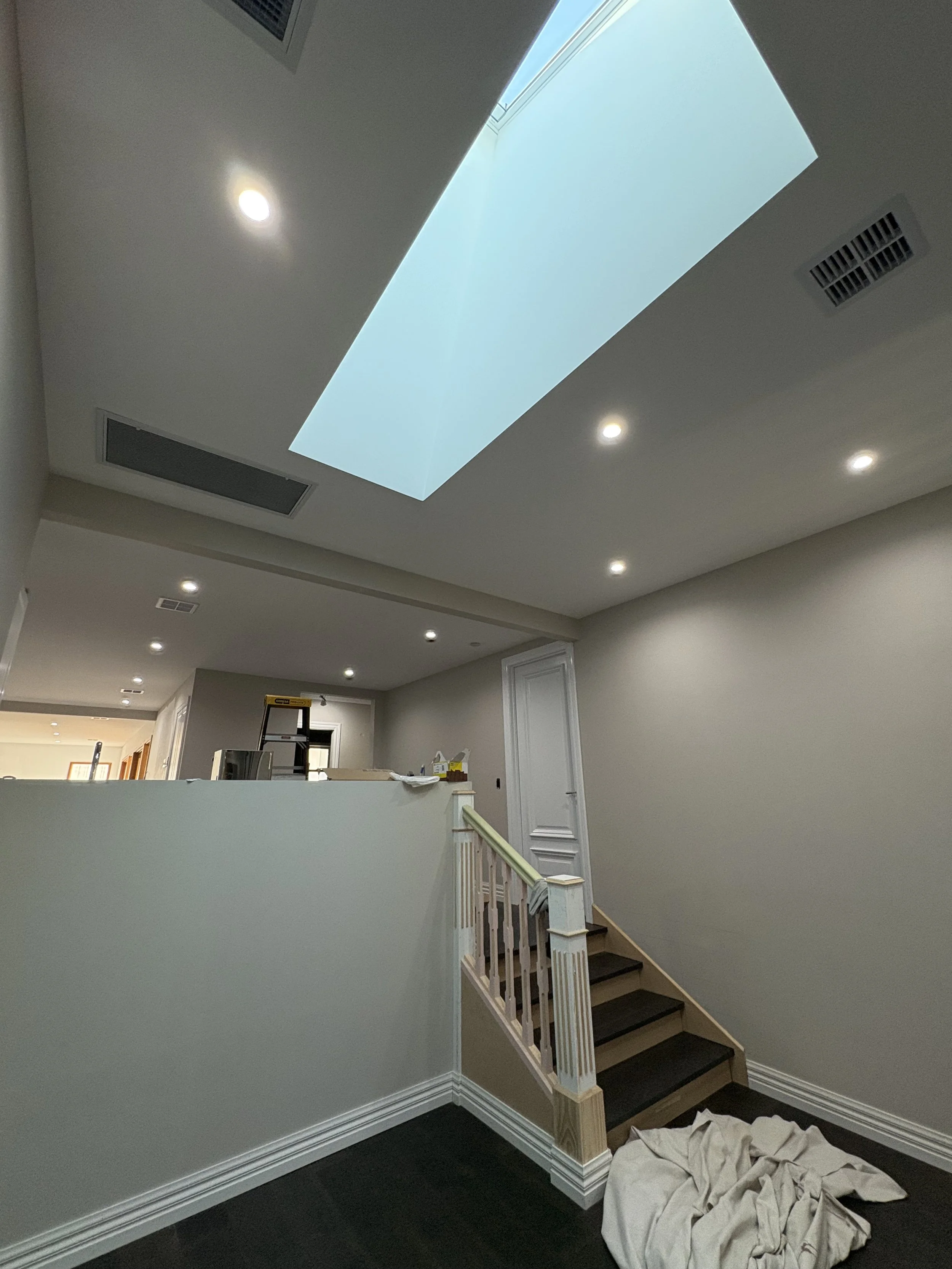 Interior of a house under construction with stairway, unfinished railing, and a skylight in the ceiling