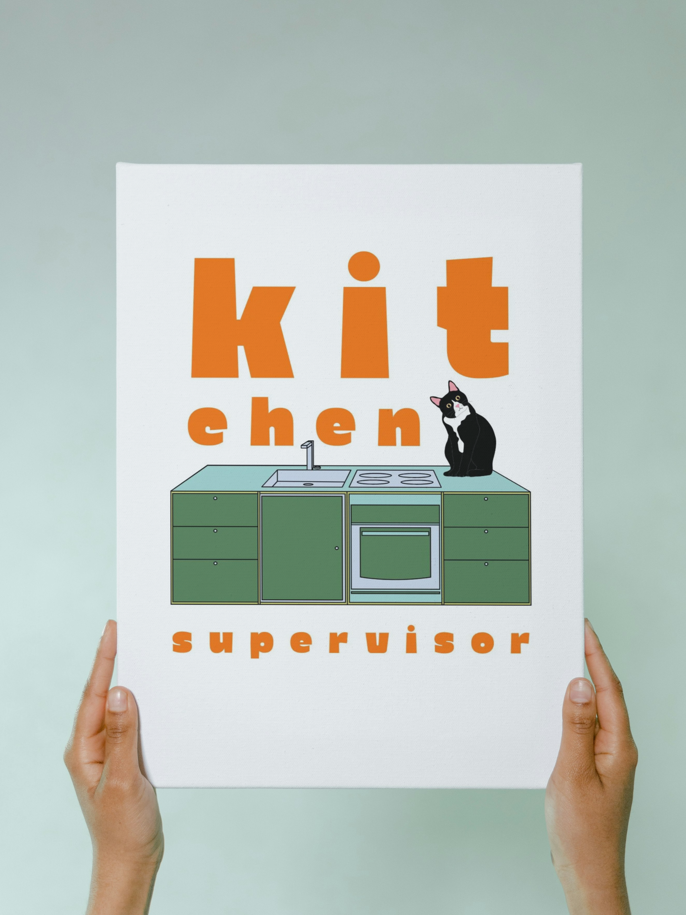 A person holding a book titled 'kitchen supervisor' with a cartoon image of a kitchen and a black and white cat sitting on top of the kitchen counter.