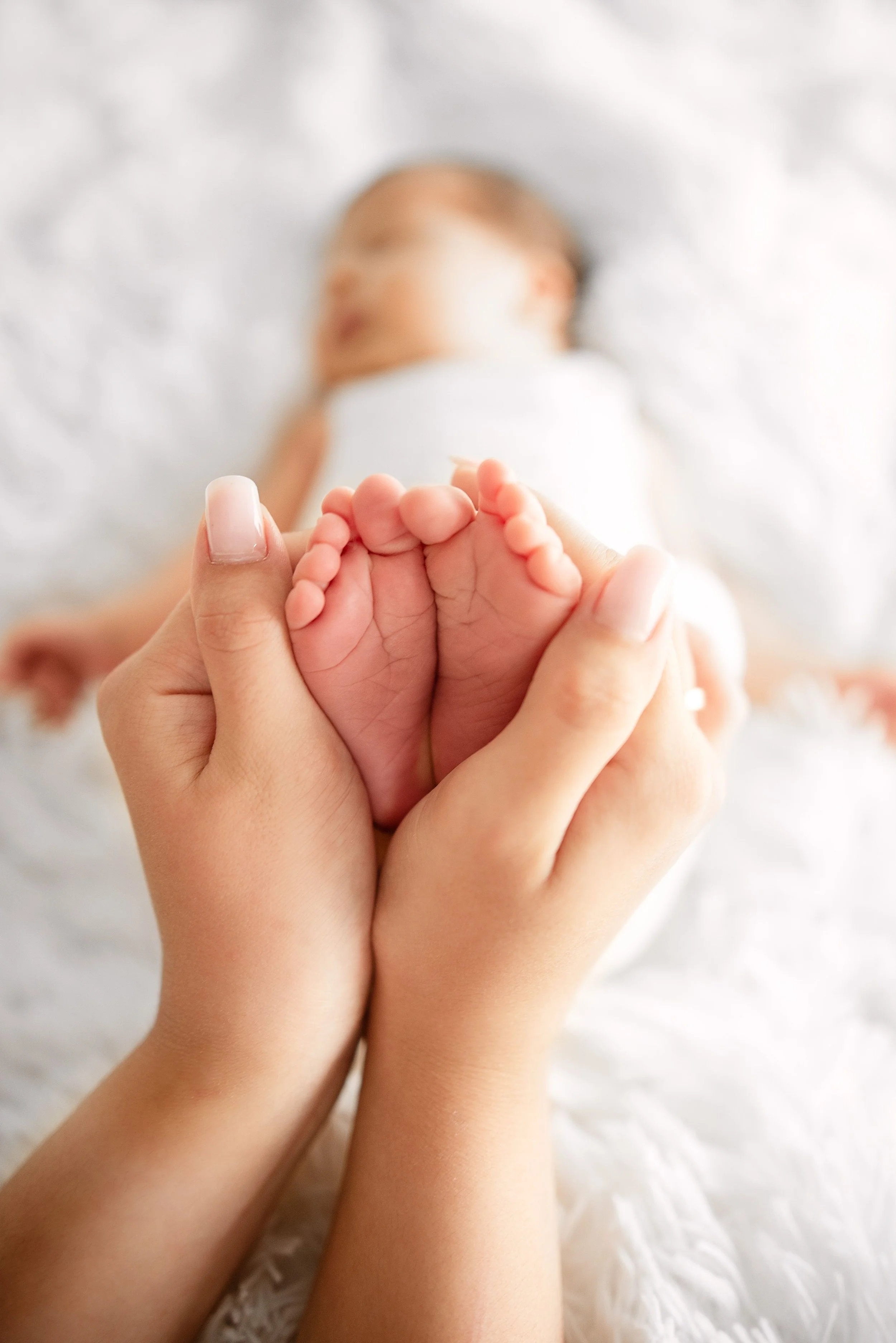 Newborn feet held gently in adult hands