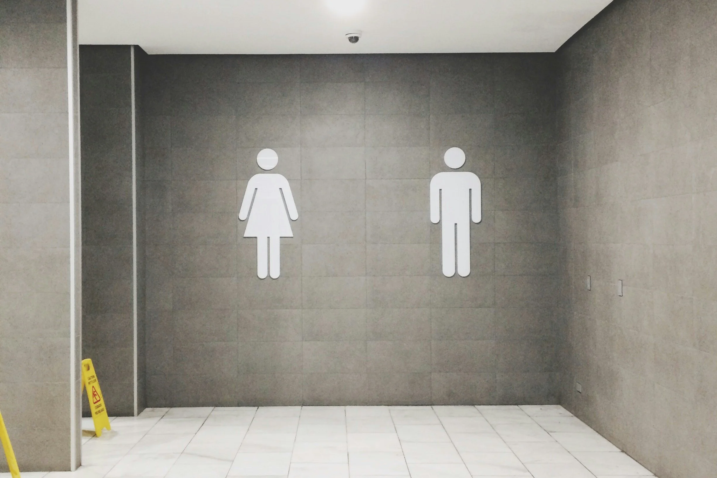 Men's and women's restroom signs on a gray wall in a public space.
