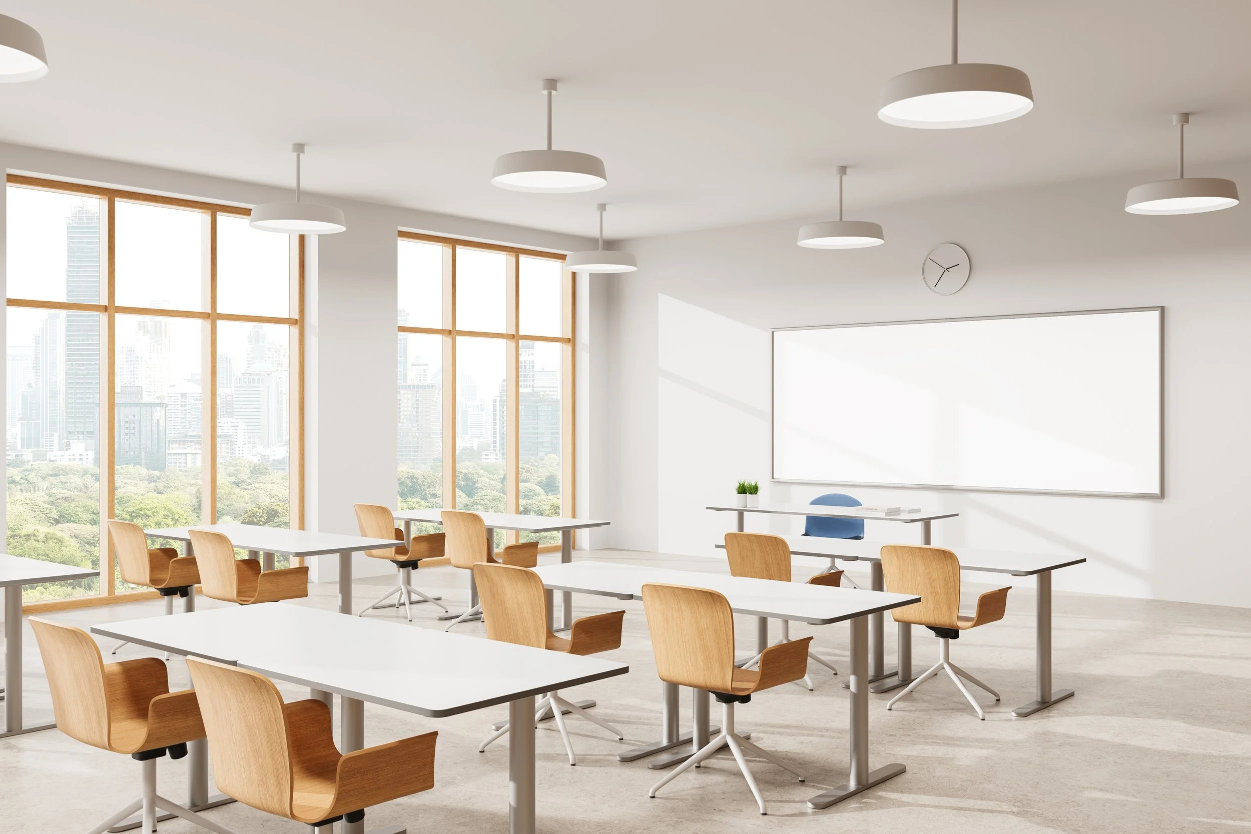 Bright modern classroom with large windows, white walls, wooden and white desks, and wooden chairs, with a whiteboard and a clock on the wall.