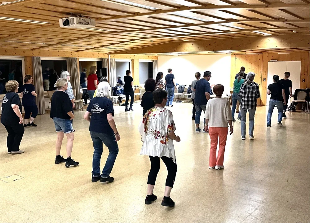Menschen in einem Tanzraum, die Tanzen üben oder eine Tanzklasse besuchen, mit Holzdecke und gespiegelt an der Wand.
