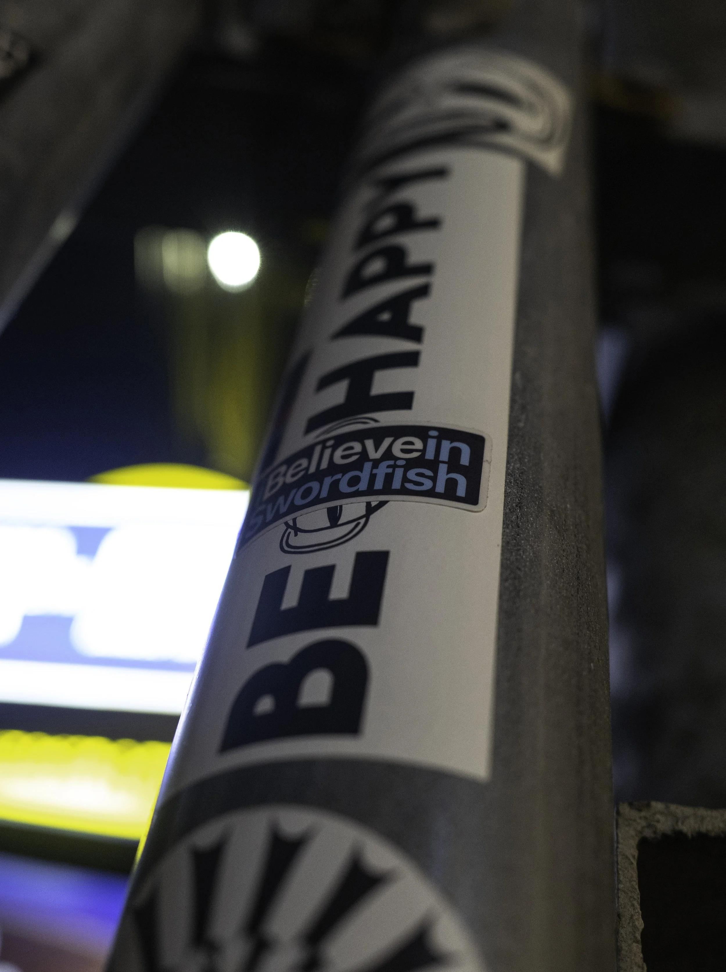 Close-up of a baseball bat with a sticker that reads 'believe in wordfish'.