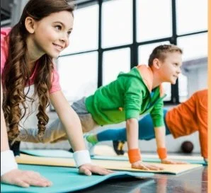 Two children participating in a yoga class on yoga mats in a bright studio.