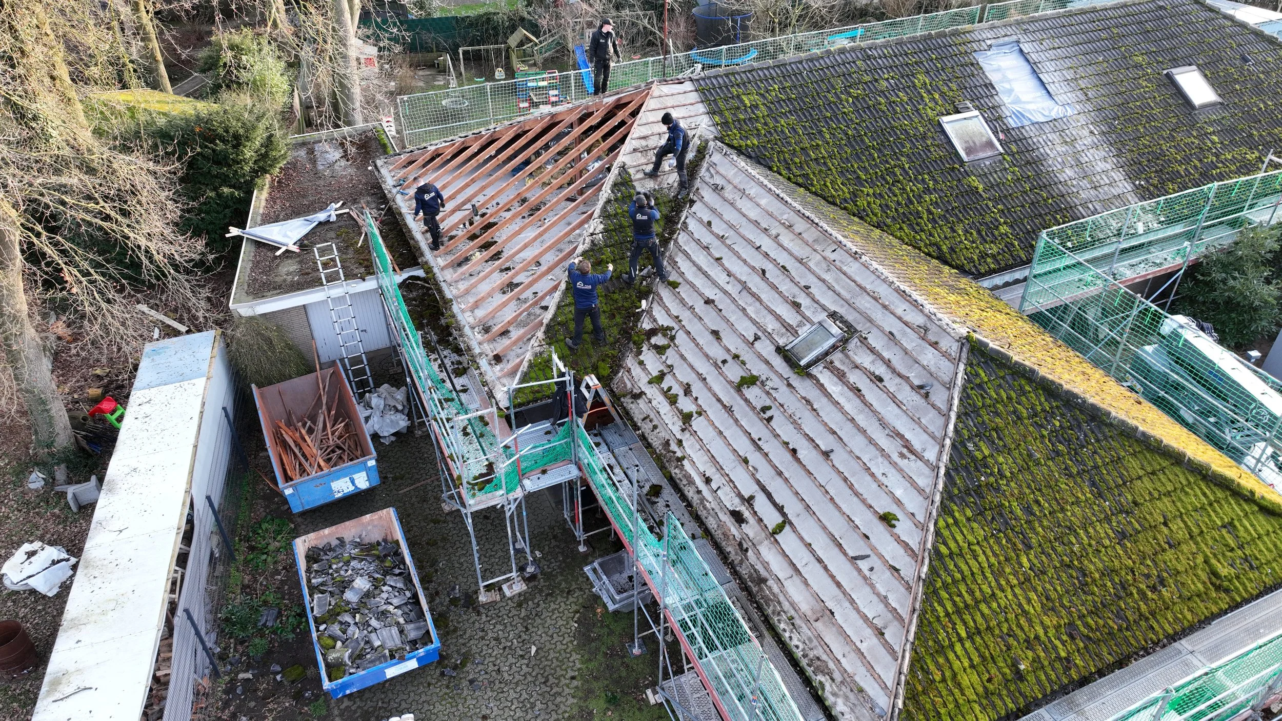 Dacharbeiten auf einem Gebäude mit mehreren Dachdeckern, die an der Dachsanierung beteiligt sind.