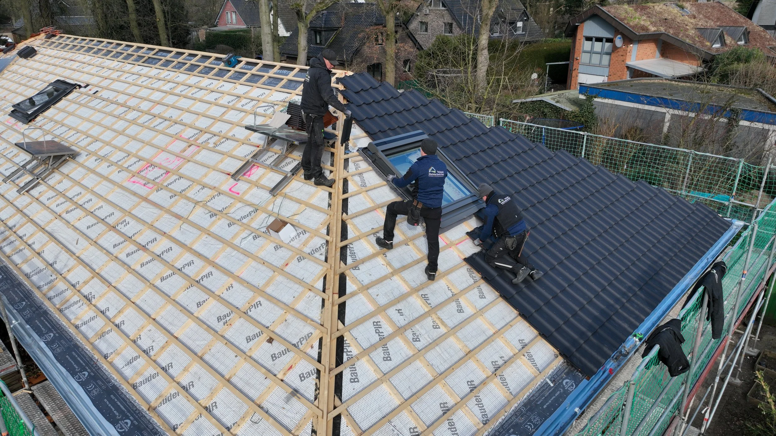 Auf einem Hausdach wird eine Dachsanierung mit neuen Dachfenstern durchgeführt. 