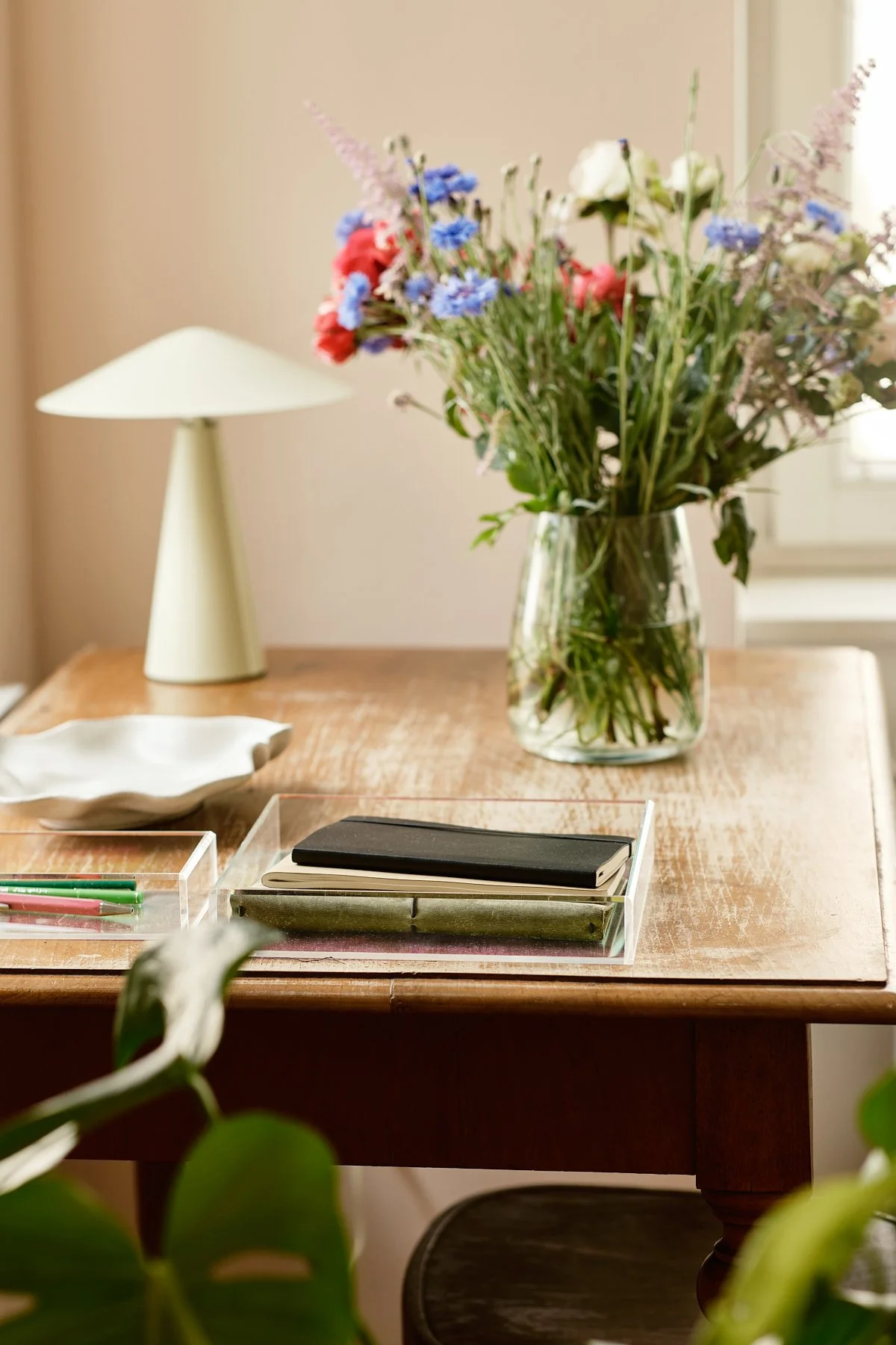 Holztisch mit Blumen, Lampe und Schreibmaterial – freundlicher Raum für Psychotherapie in Wien.