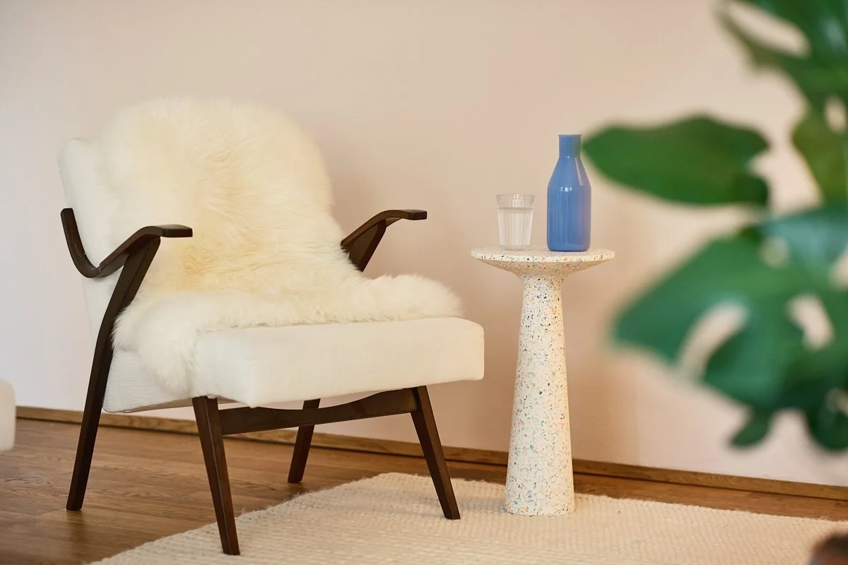 Praxisraum-Therapiestuhl mit Fell und Wasserglas – einladende Umgebung für Einzelgespräche in Wien 1050.
