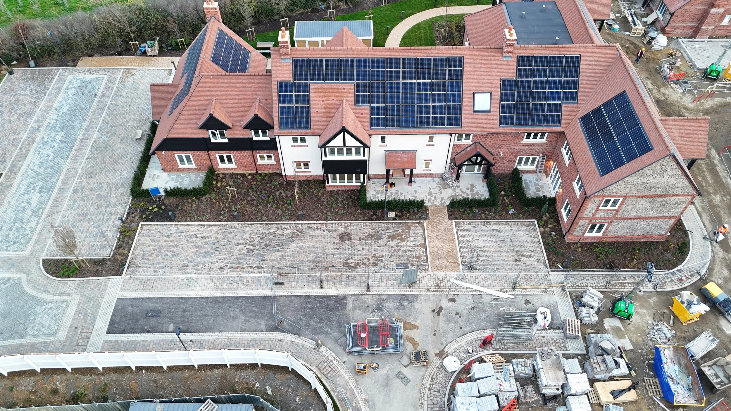 Aerial view of a residential building with solar panels on the roof, surrounded by a courtyard and ongoing construction work.