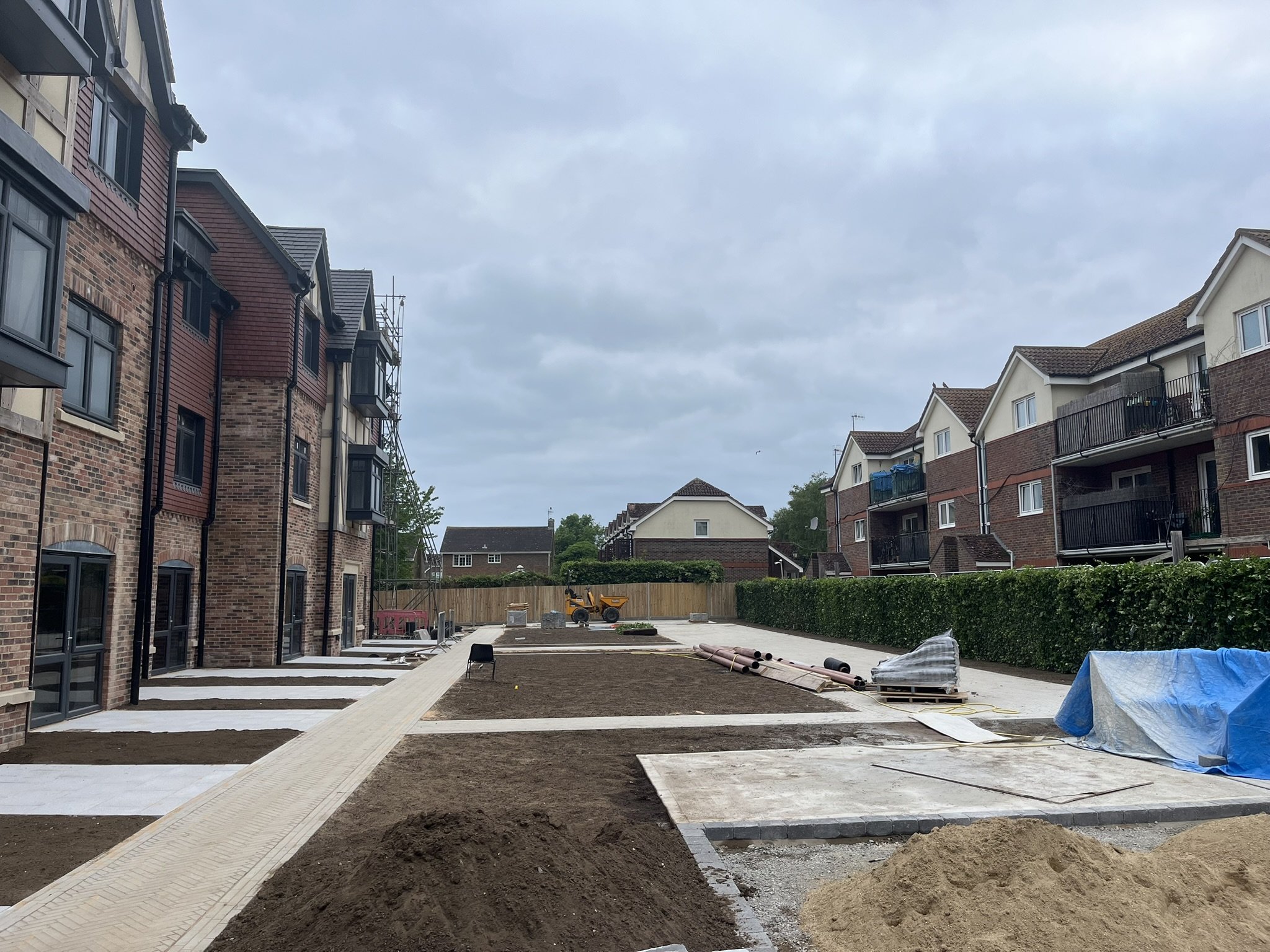 Under construction pathway with newly laid concrete, construction materials, and equipment in a residential area.