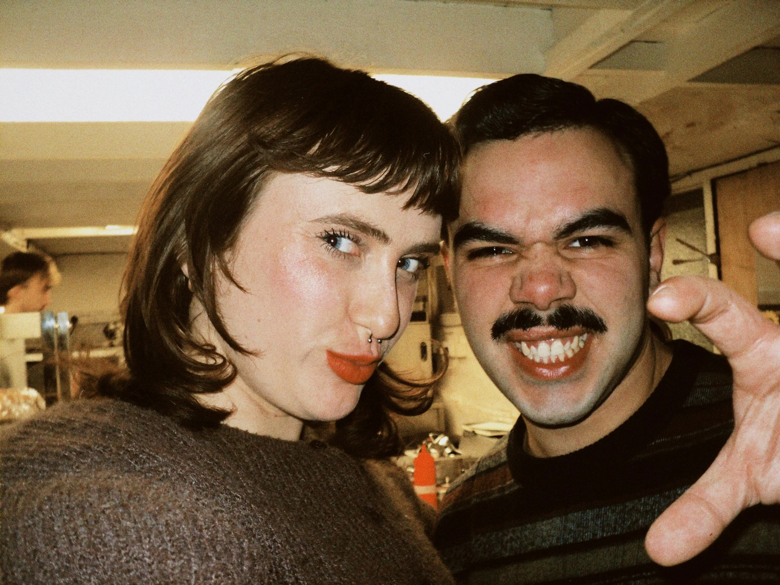 A close-up photo of a woman and a man smiling, posing for a selfie in an indoor setting.