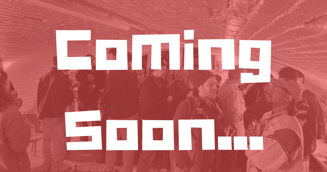 People gathered in an indoor space with brick walls and a low arched ceiling, socializing and holding drinks, with a large overlay text that says 'Coming soon...' in bold, white font.