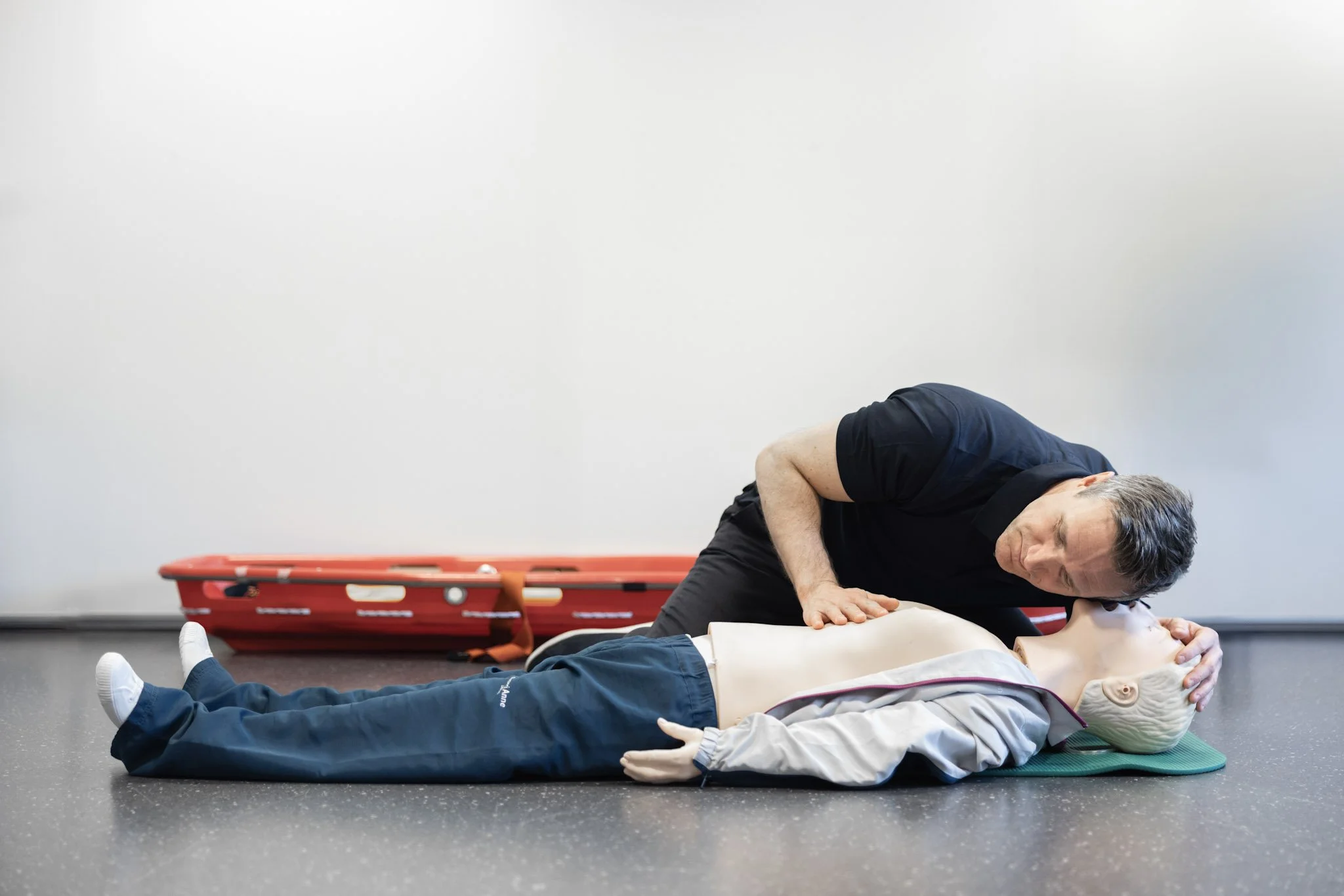 En mann utfører hjertelunge-redning på en dukke under en førstehjelpsopplæring.