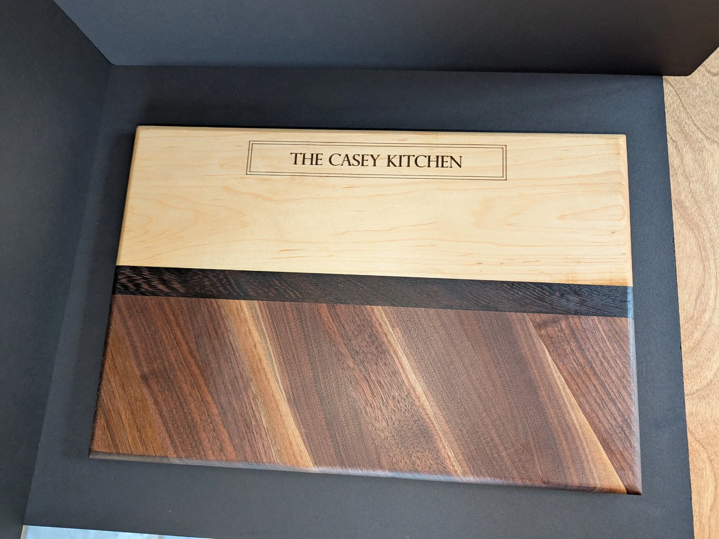 Wooden sample board with the label 'The Casey Kitchen' on top; the board contains sections of light, dark, and medium stained wood.