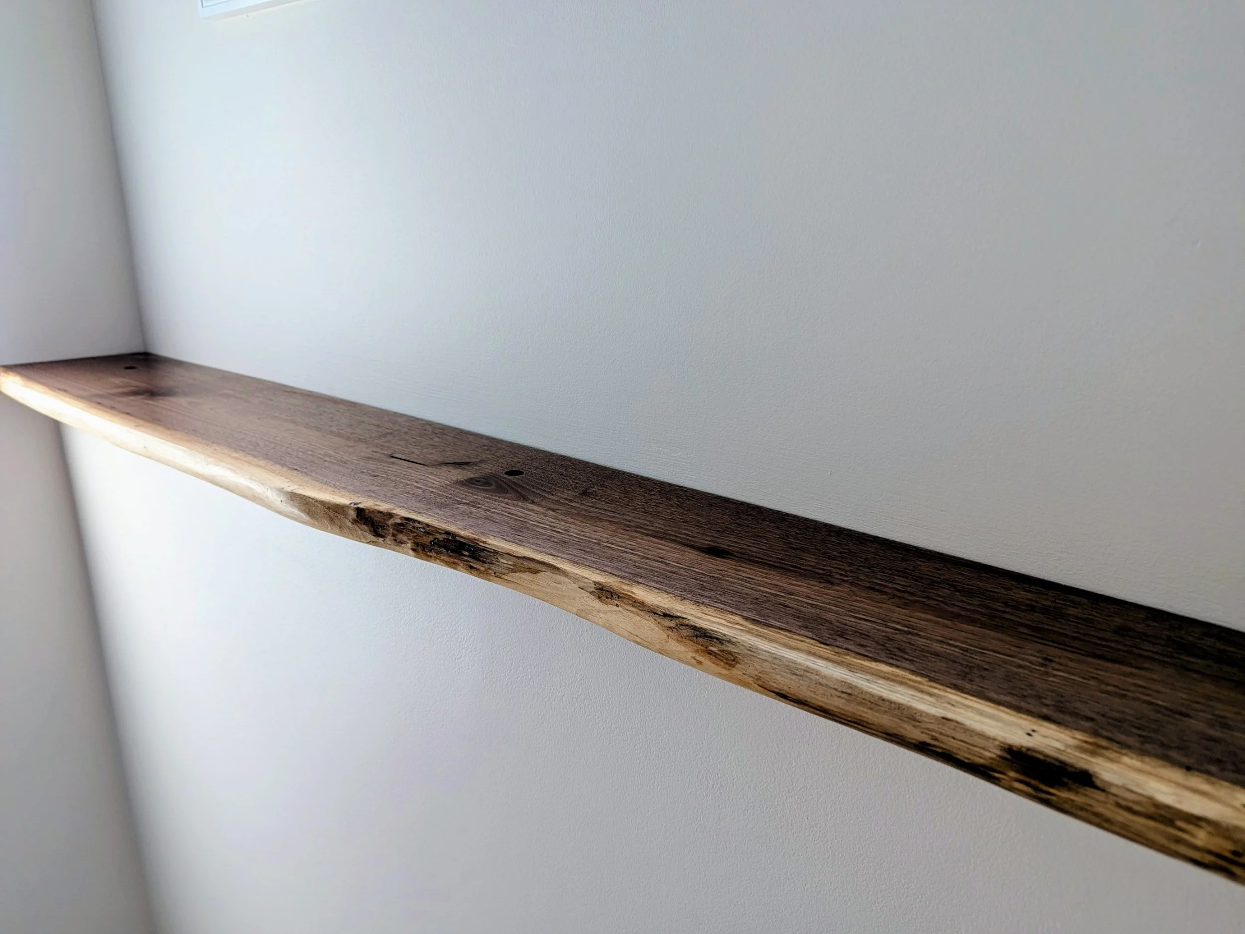 Close-up of a wooden shelf mounted on a white wall
