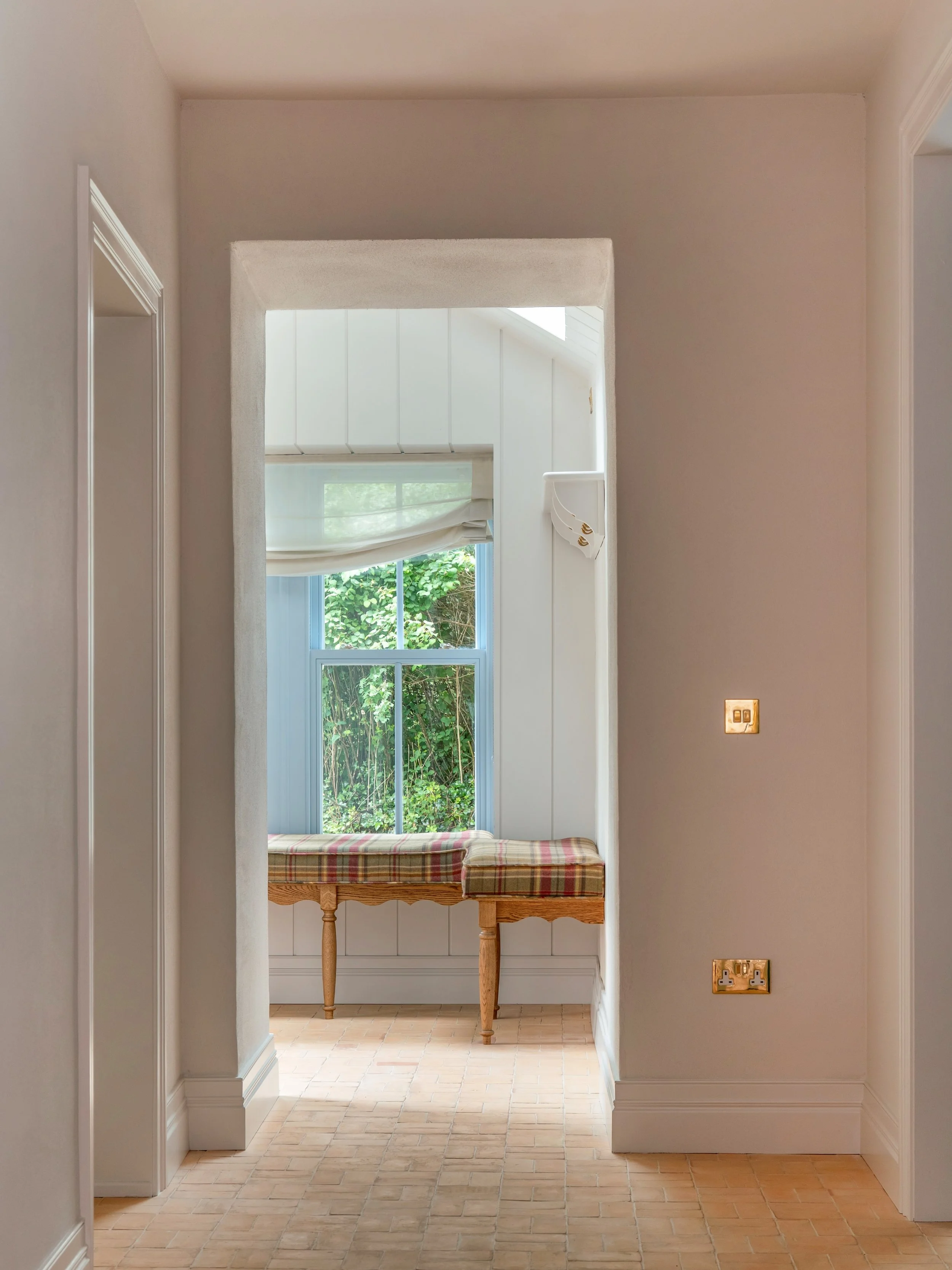 The porch at Deerpark Residence may be small, but it works hard.

The seating beneath the window for pulling off muddy boots and hooks close by for everyday coats, everything has its place. The blue painted window, checked cushions and view into the 