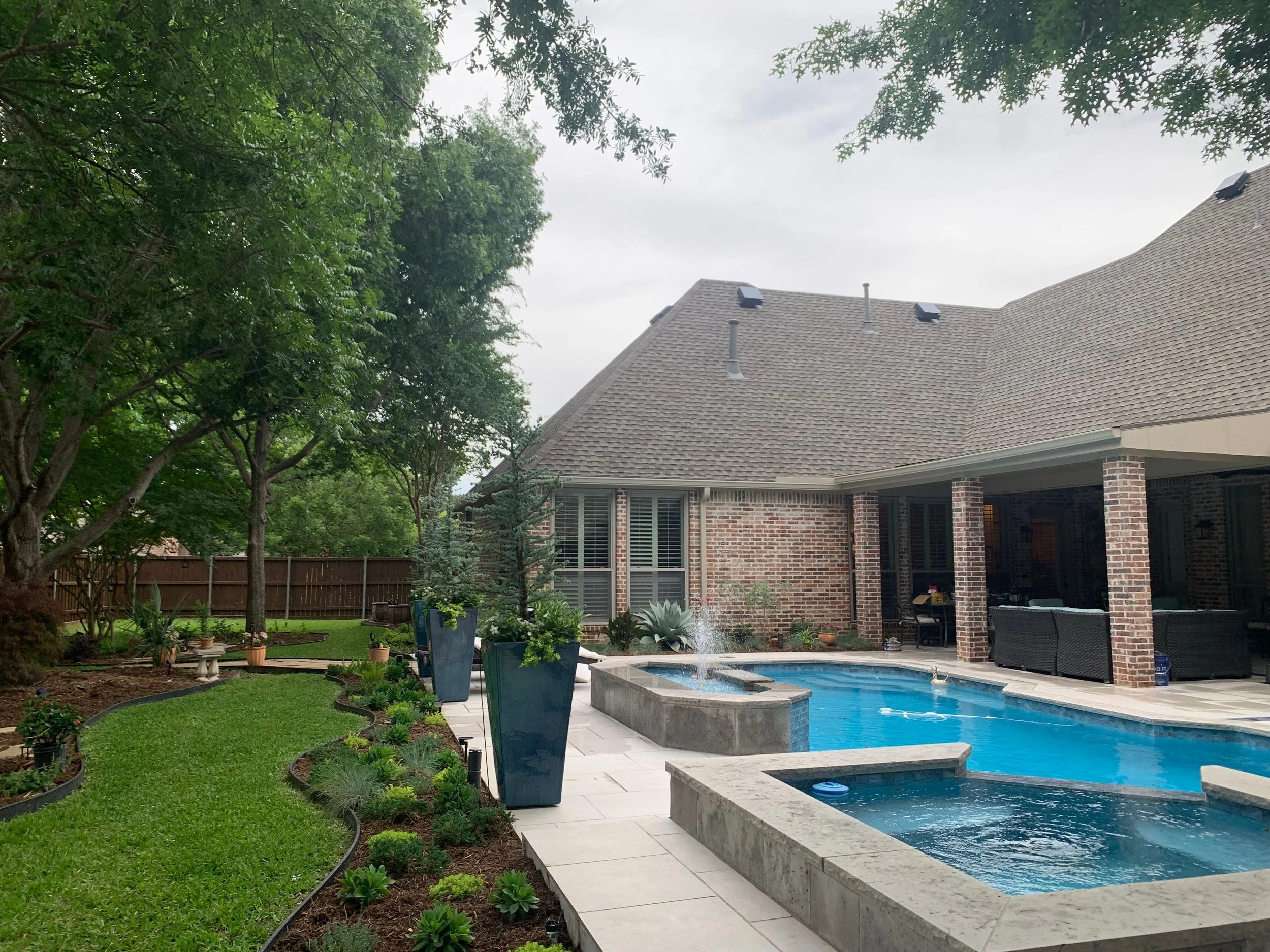 Landscape: Custom planting beds to bring cohesion between the existing deciduous trees and new Juniper Taylors with the various colorful perennials 
