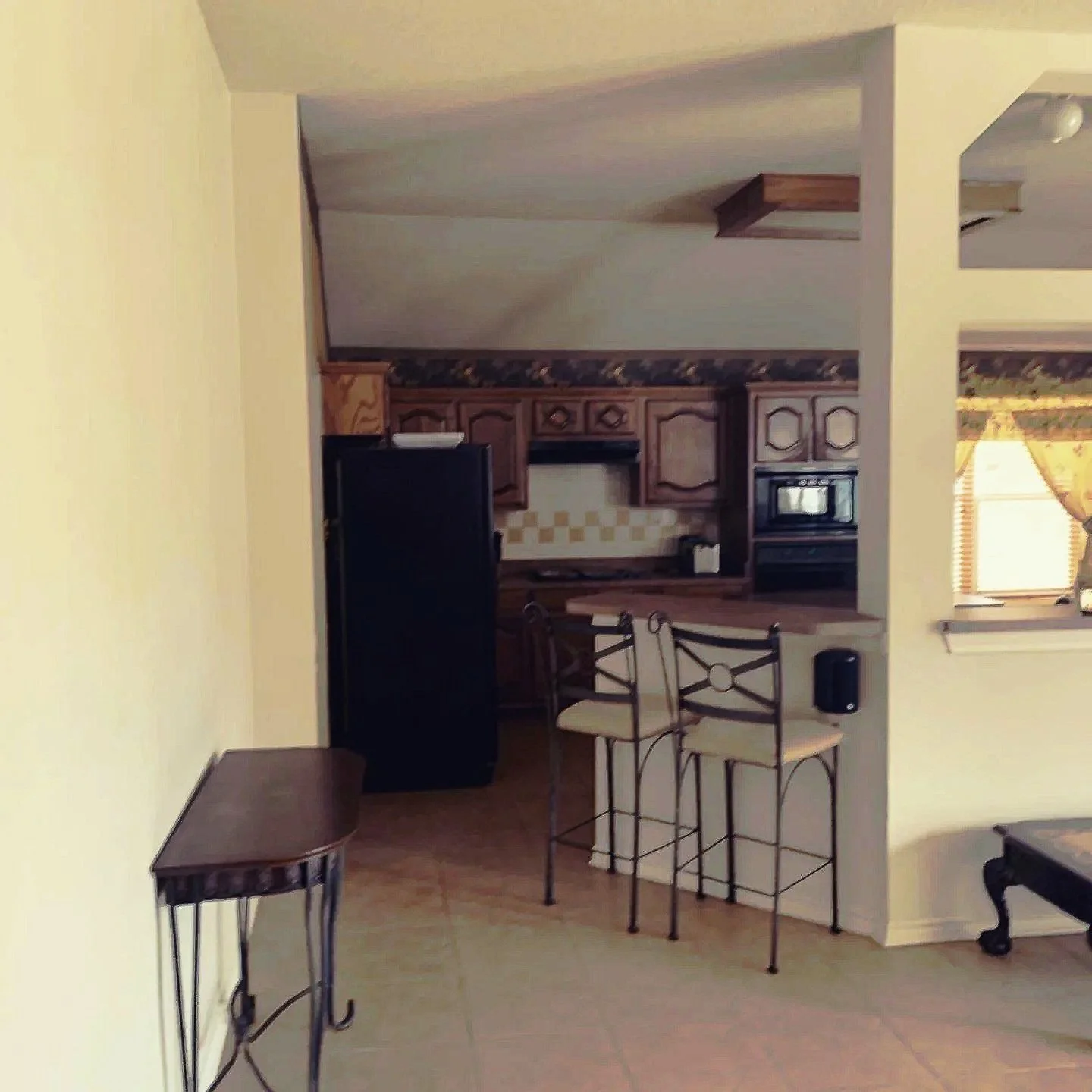 Kitchen: Original cabinetry, lighting, countertops, wallpaper, and appliances combined created a dark, fragmented space (Before)