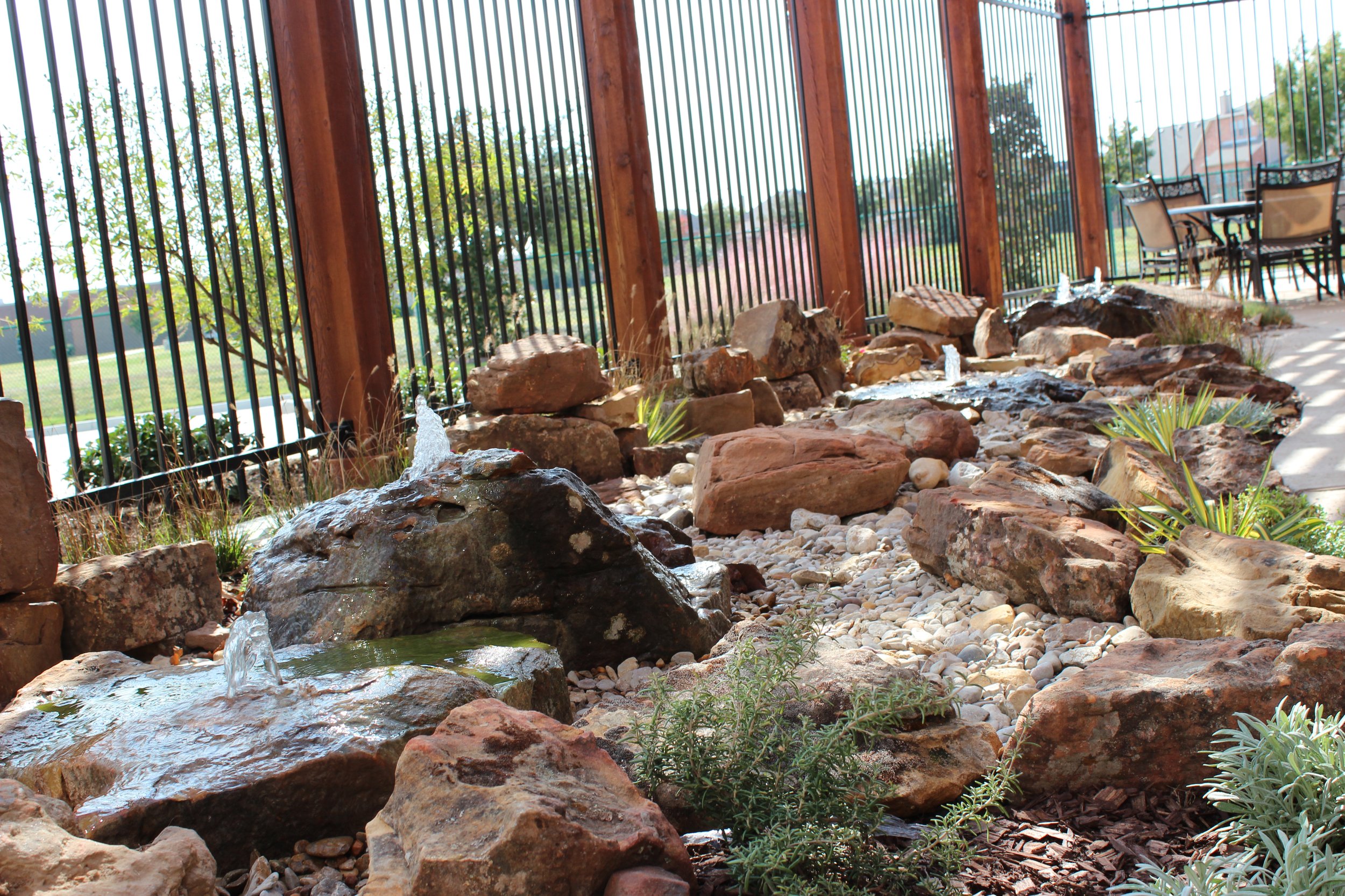 Landscape: Custom native, drought-tolerant plantings accented by multi-sized boulders and a bespoke fountain carved from a natural stone boulder