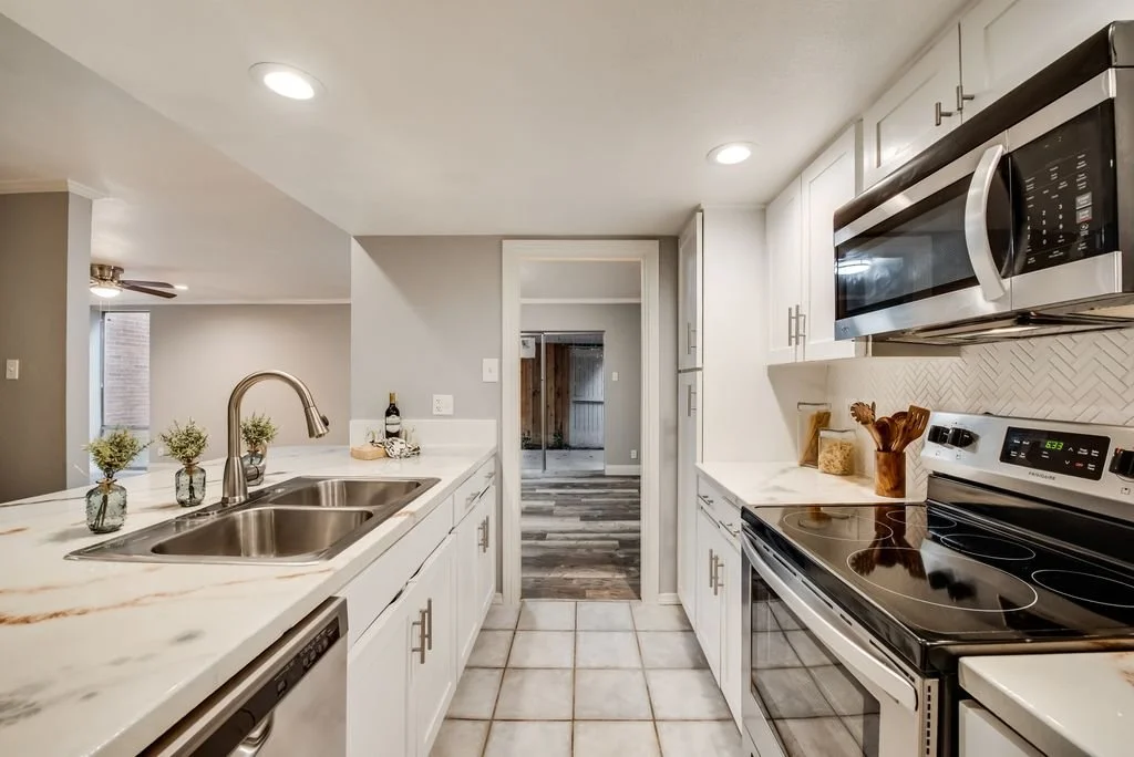 Kitchen: Optimized color palette and original lighting utilized to enhance the sense of scale and openness in a narrow layout