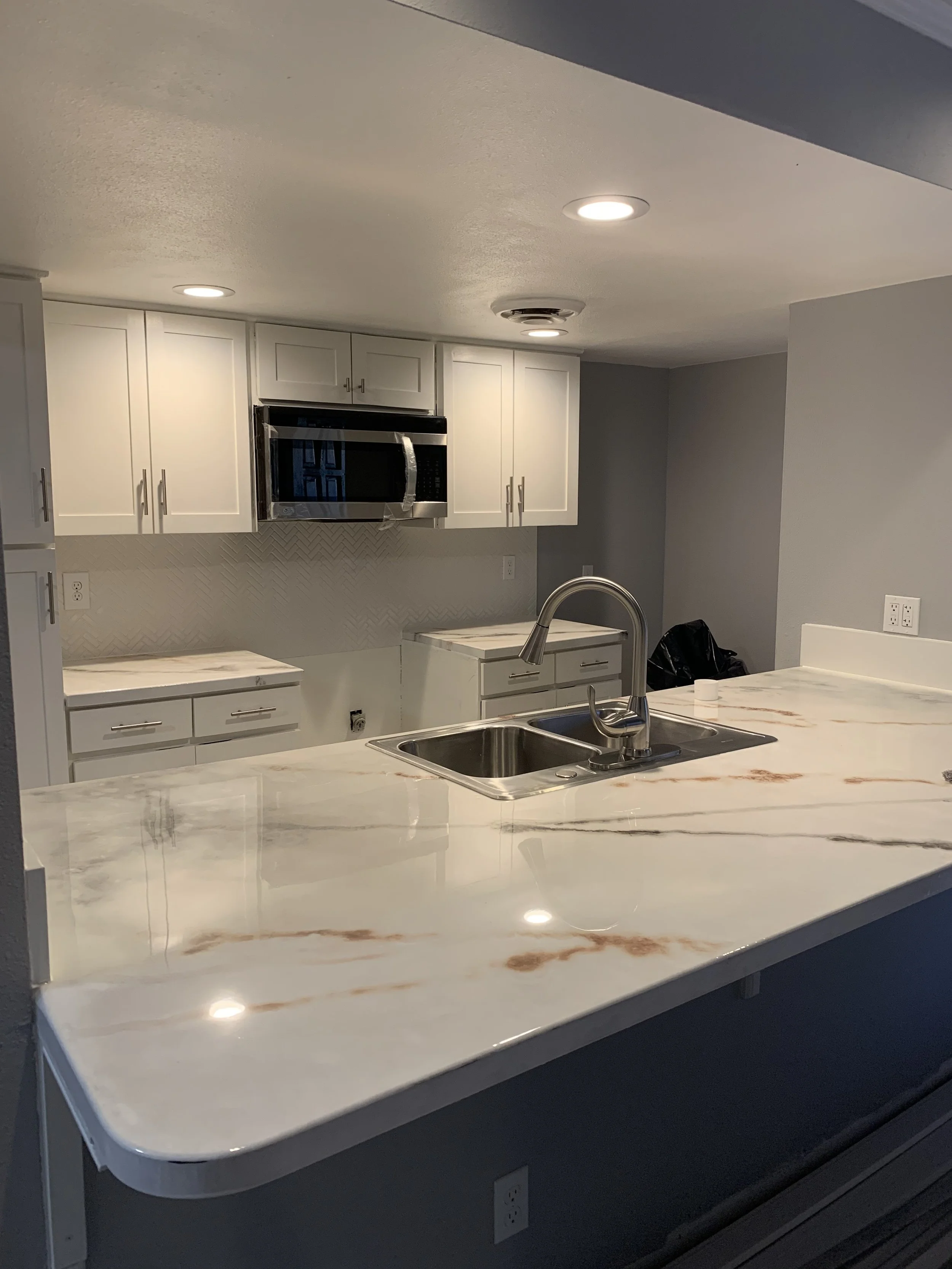 Kitchen: New epoxy countertops and backsplash paired with existing cabinetry - updated with custom 1x wood accents - and a refined color palette to elevate the existing lighting