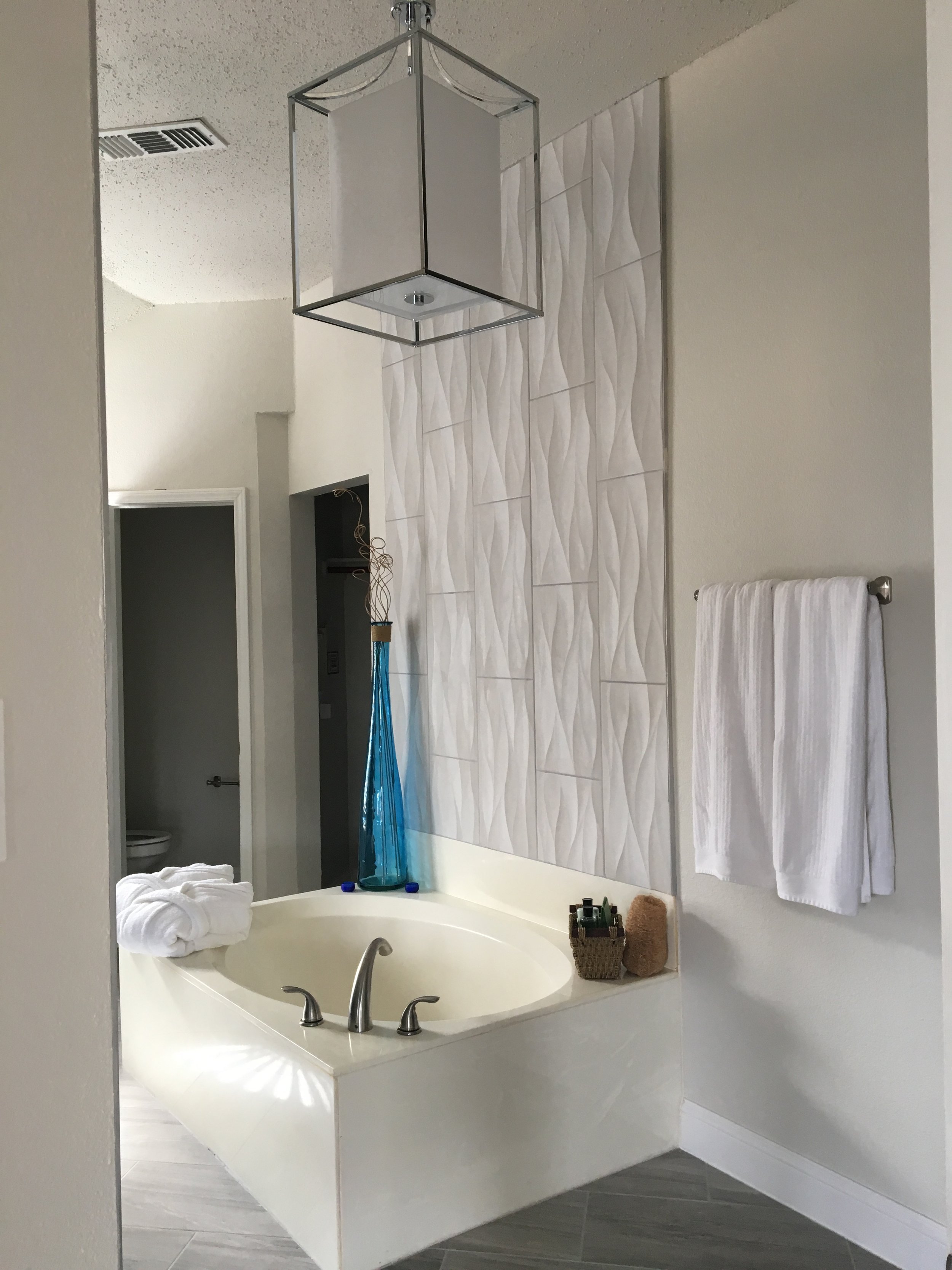 Primary Bathroom: New lighting with custom wall tiling designed for a water-cascading aesthetic