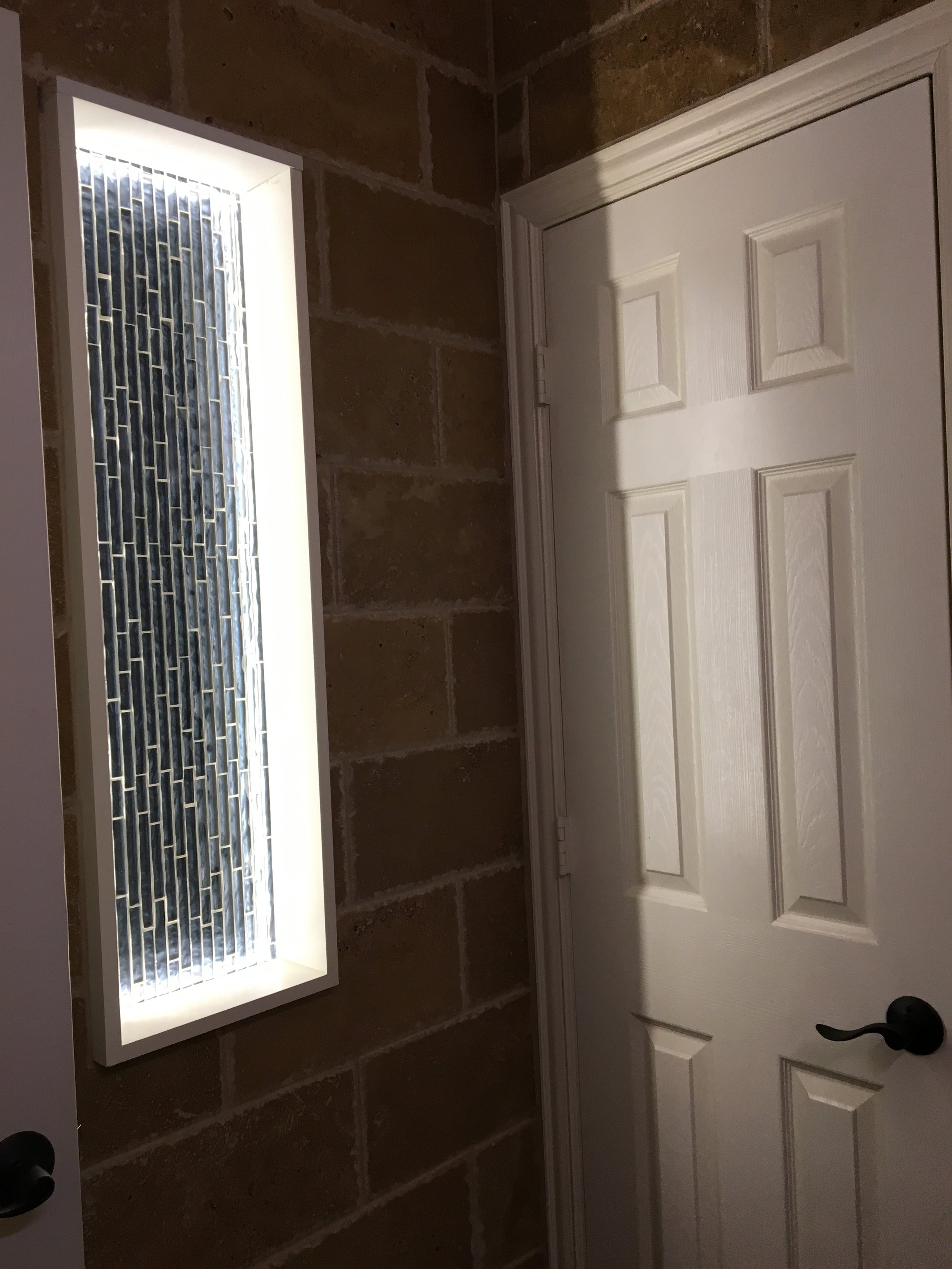 Half Bathroom: Integrated wall niche with accent LED lighting, continuing the waterfall cascade design