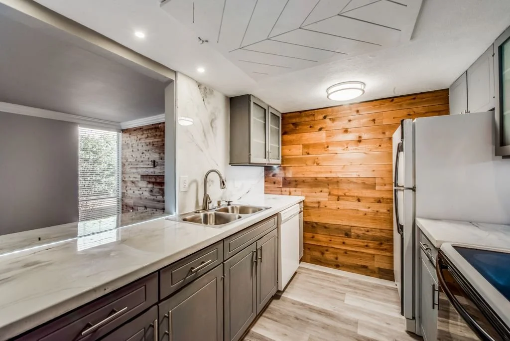 Kitchen: New epoxy surfaces and a custom wood accent wall with matching ceiling panel, custom cabinetry, and lighting