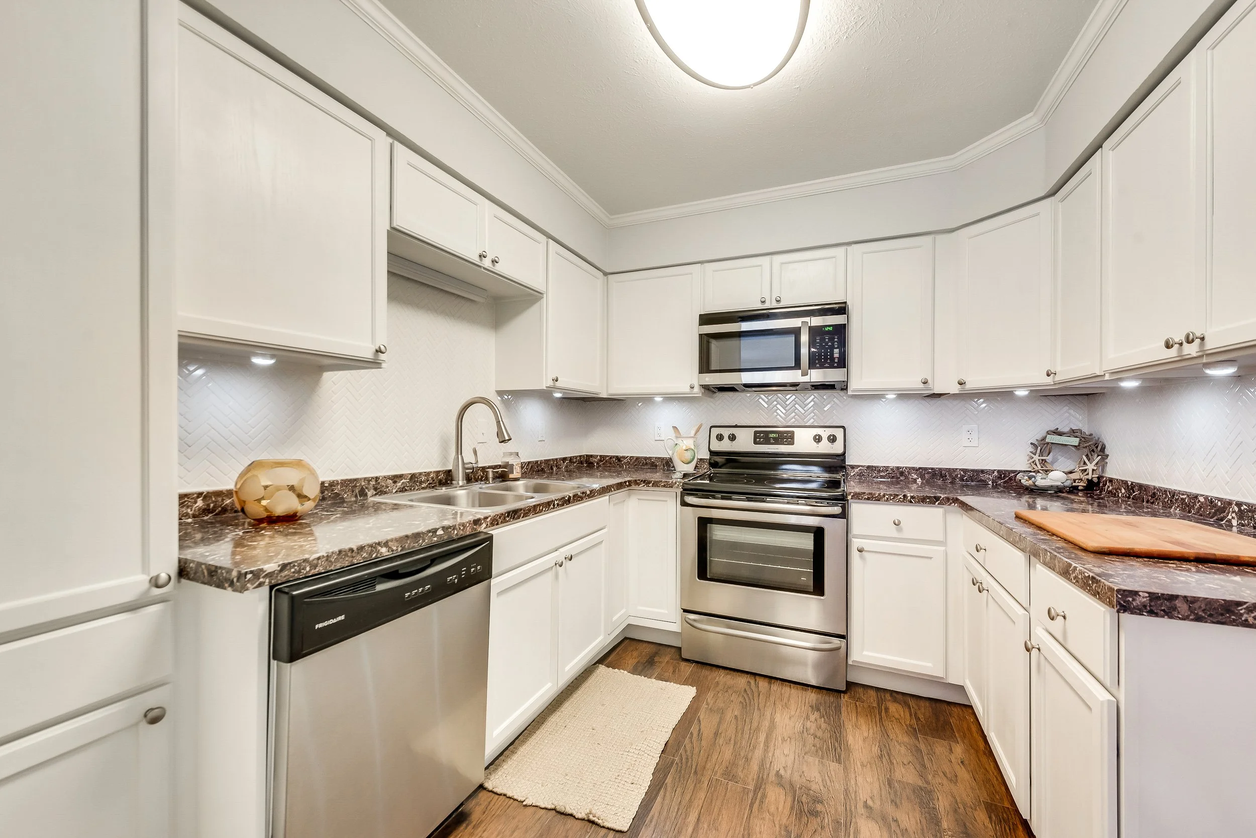 Kitchen: New backsplash and integrated lighting paired with a refined color palette to maximize light and space